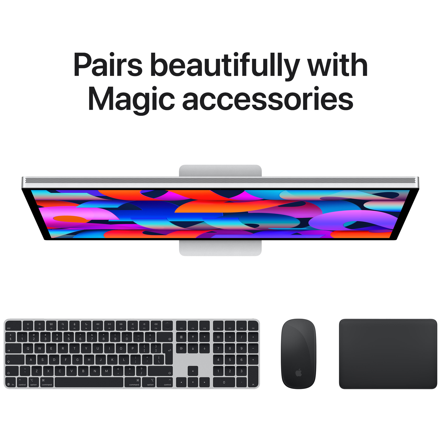 An iMac with a colorful display, keyboard, mouse, and trackpad.