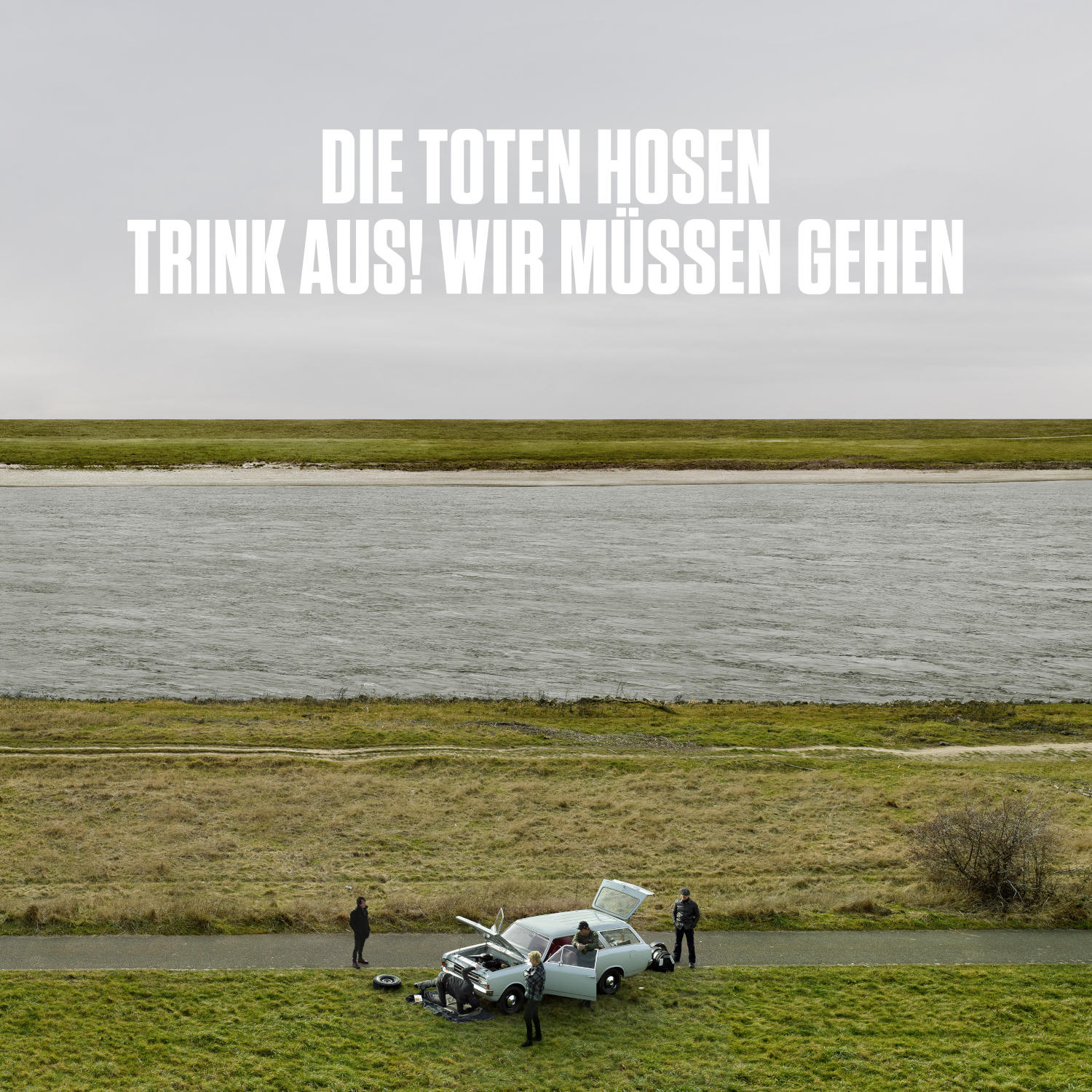 Menschen stehen neben einem offenen Auto an einem Deich.