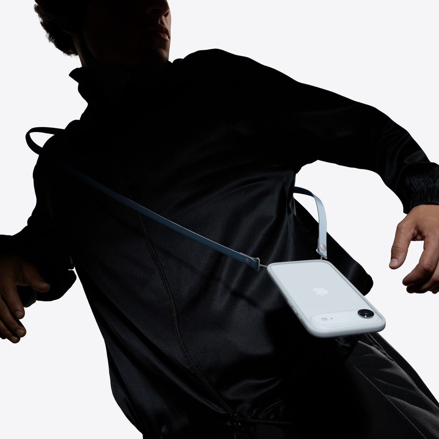Personne en vêtement noir portant un iPhone gris clair sur une lanière bleue.