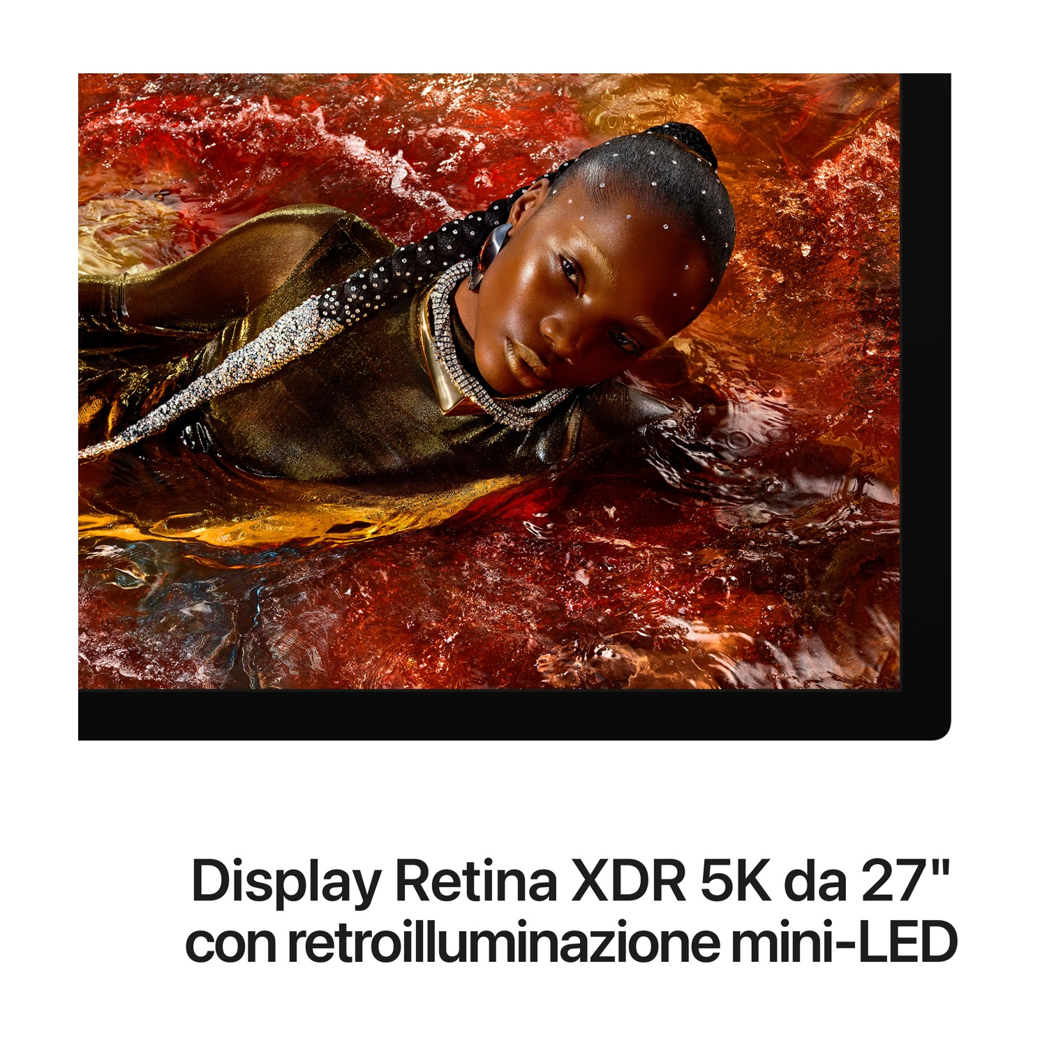 Una persona con glitter sul viso giace in acqua rossa e vorticosa con un vestito dorato.