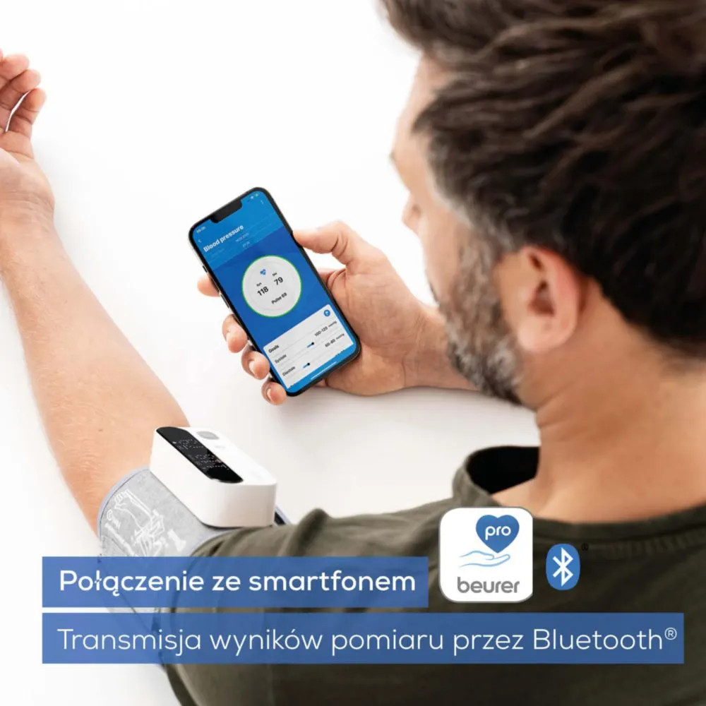 Mężczyzna mierzy ciśnienie krwi urządzeniem i aplikacją na smartfon przez Bluetooth.