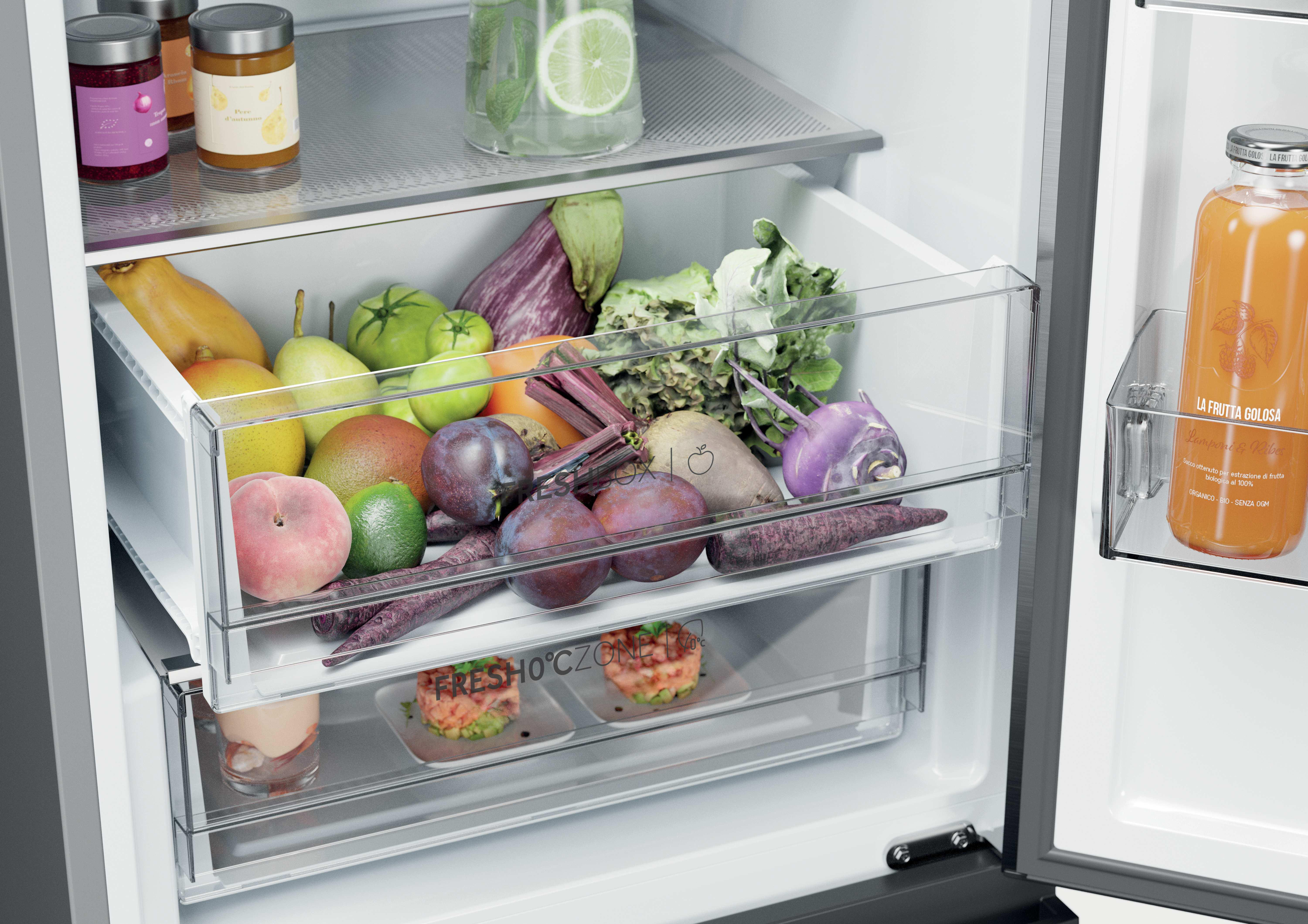 Ein offener Kühlschrank mit Obst und Gemüse in Schubladen.