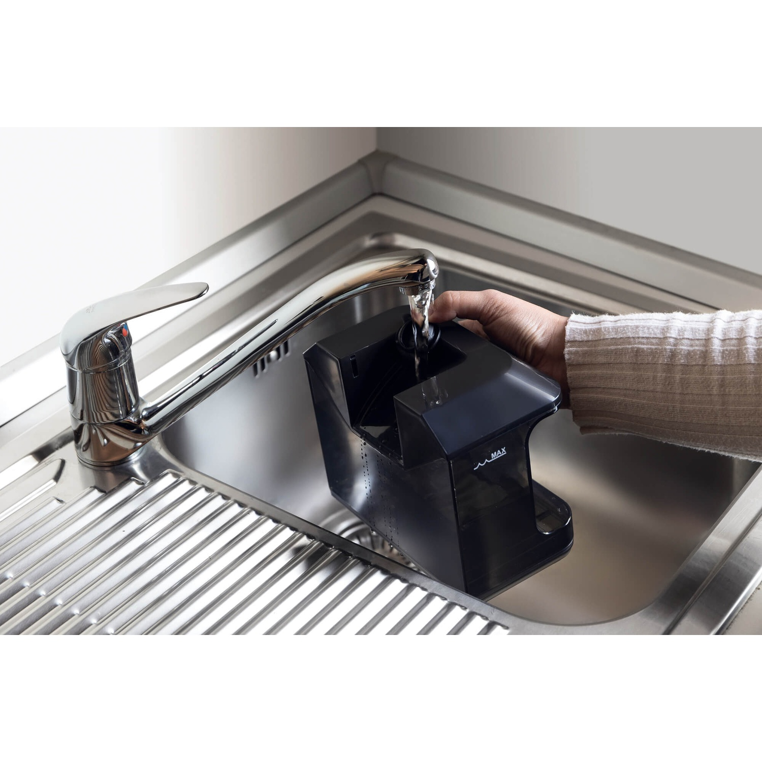 Una mano riempie un contenitore nero sotto l'acqua corrente in un lavandino.