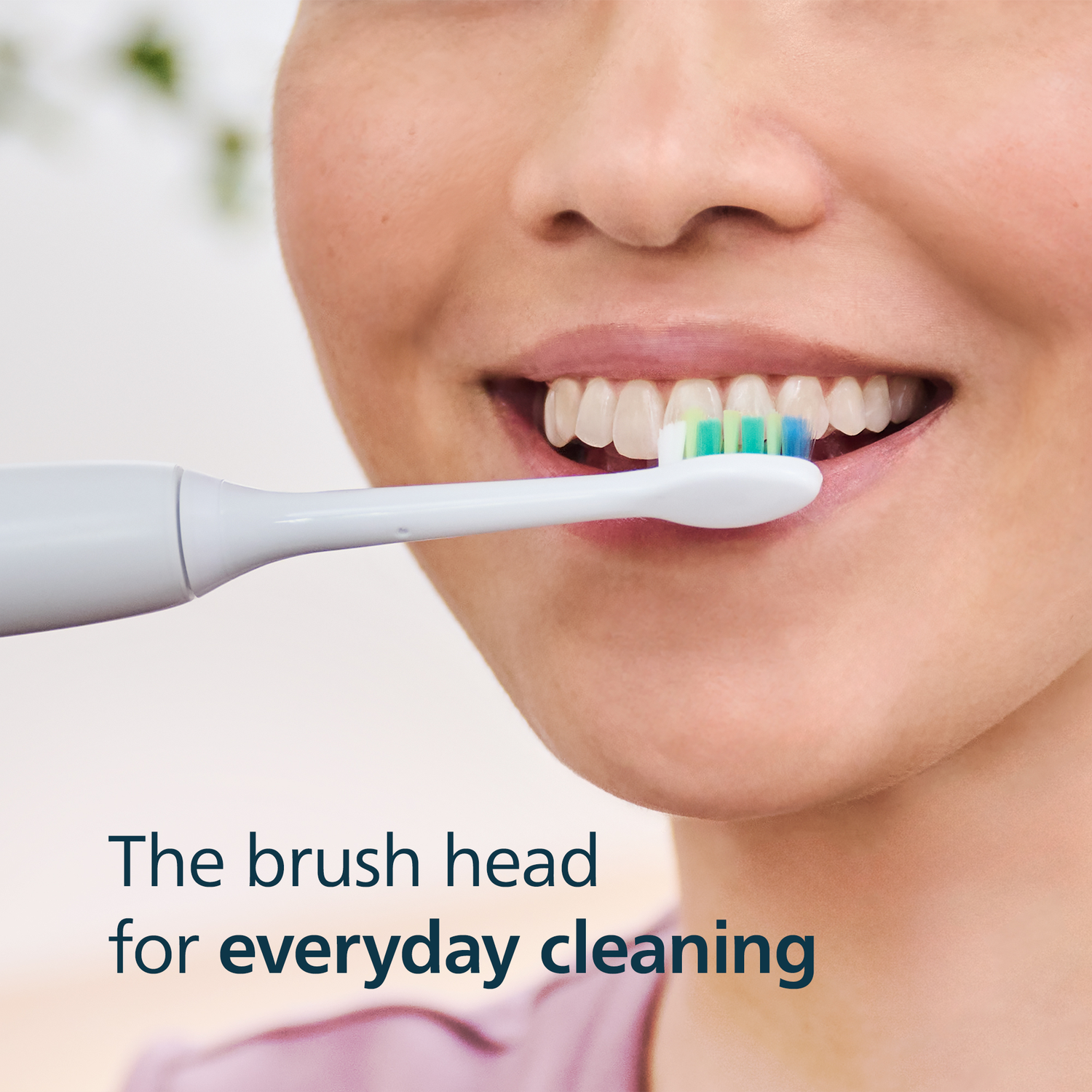 A woman brushes her teeth with an electric toothbrush.