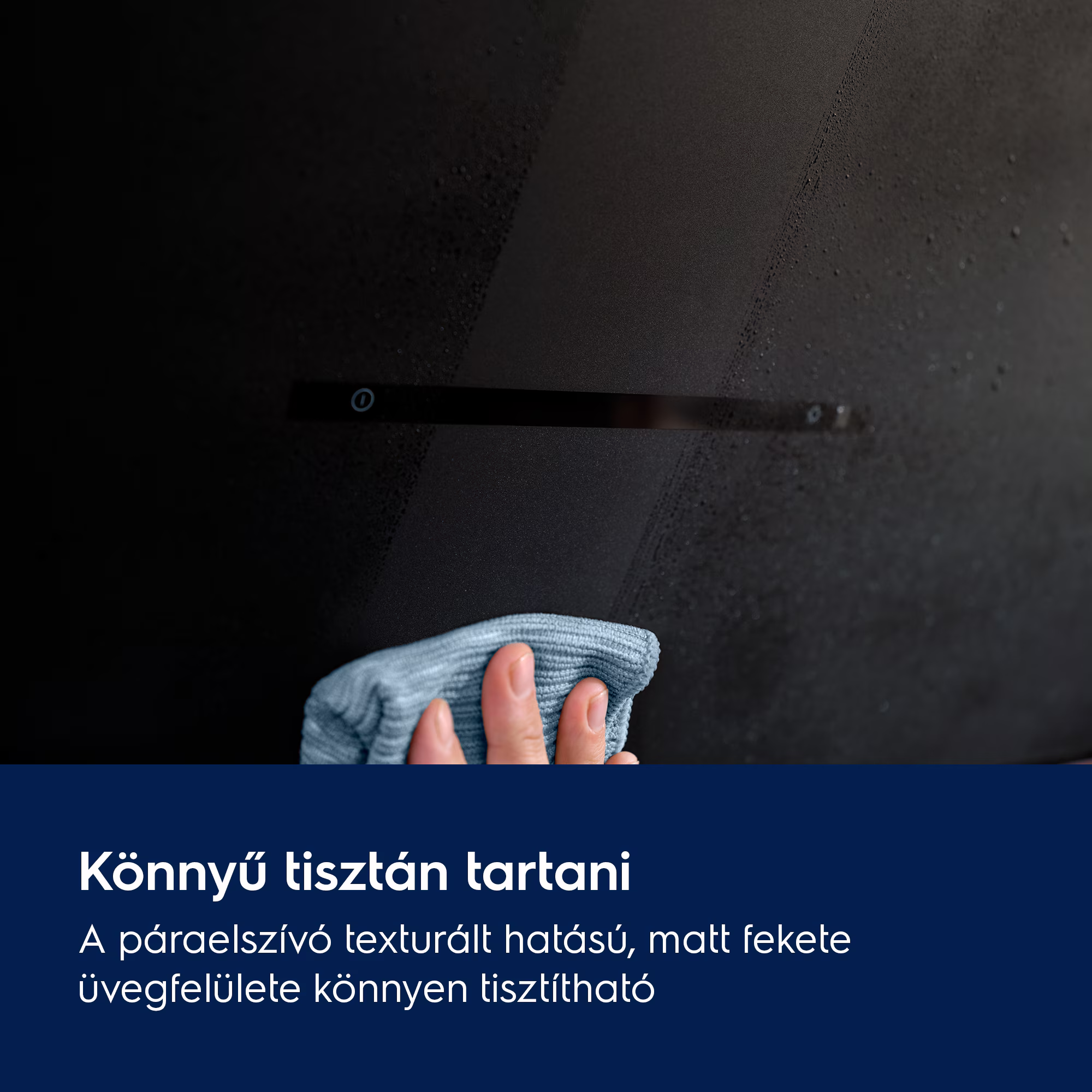 Egy kéz kék ruhával töröl le egy vízcseppes fekete felületet.