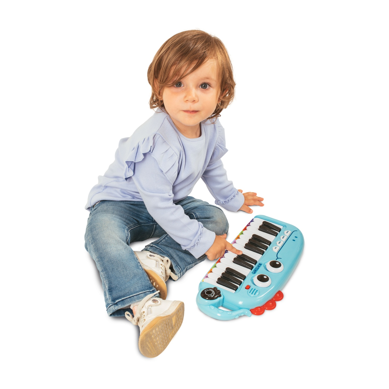 Un bambino piccolo in jeans blu suona un pianoforte giocattolo blu con occhi.