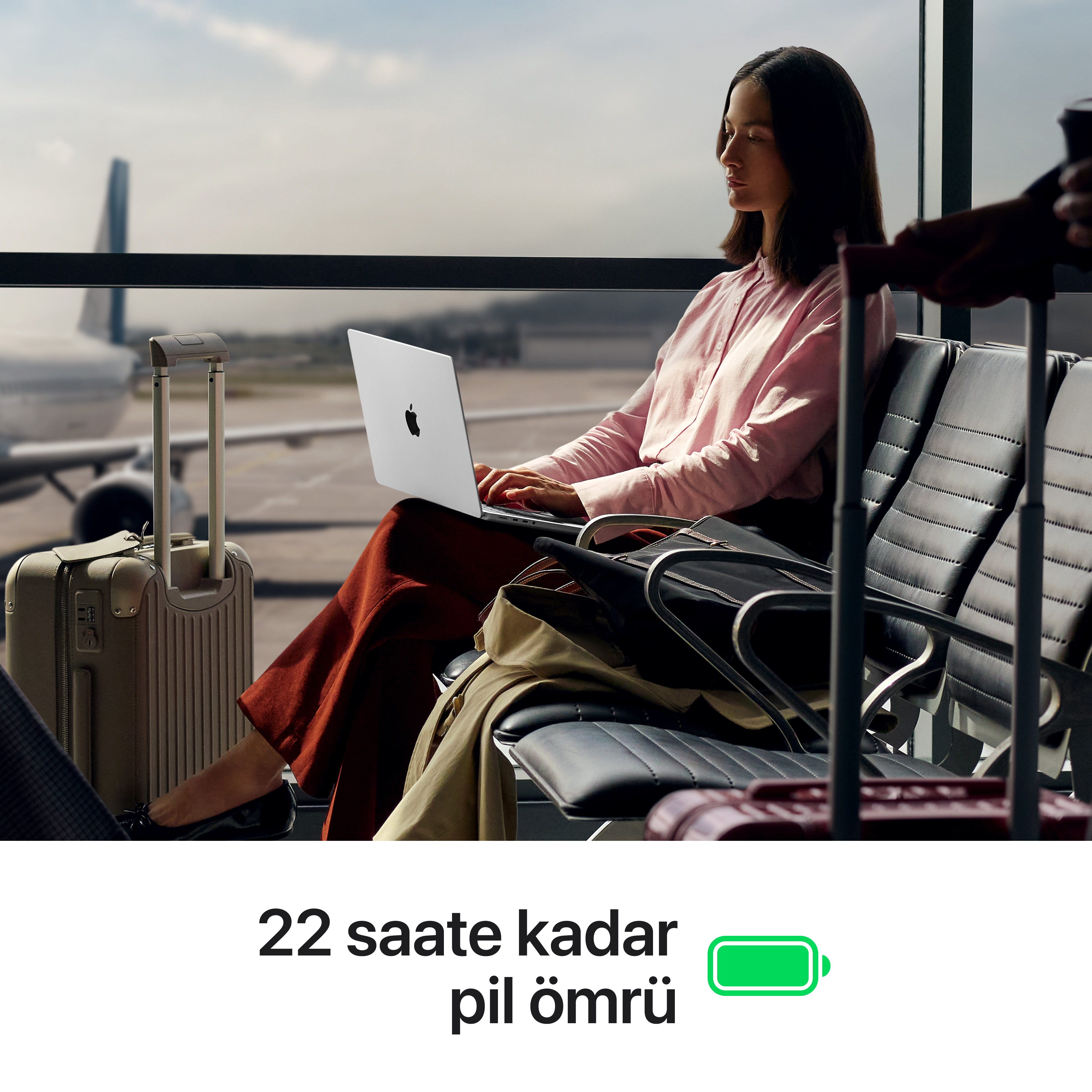 Bir kadın uçak yanında havaalanı bekleme alanında dizüstü bilgisayarda çalışıyor.