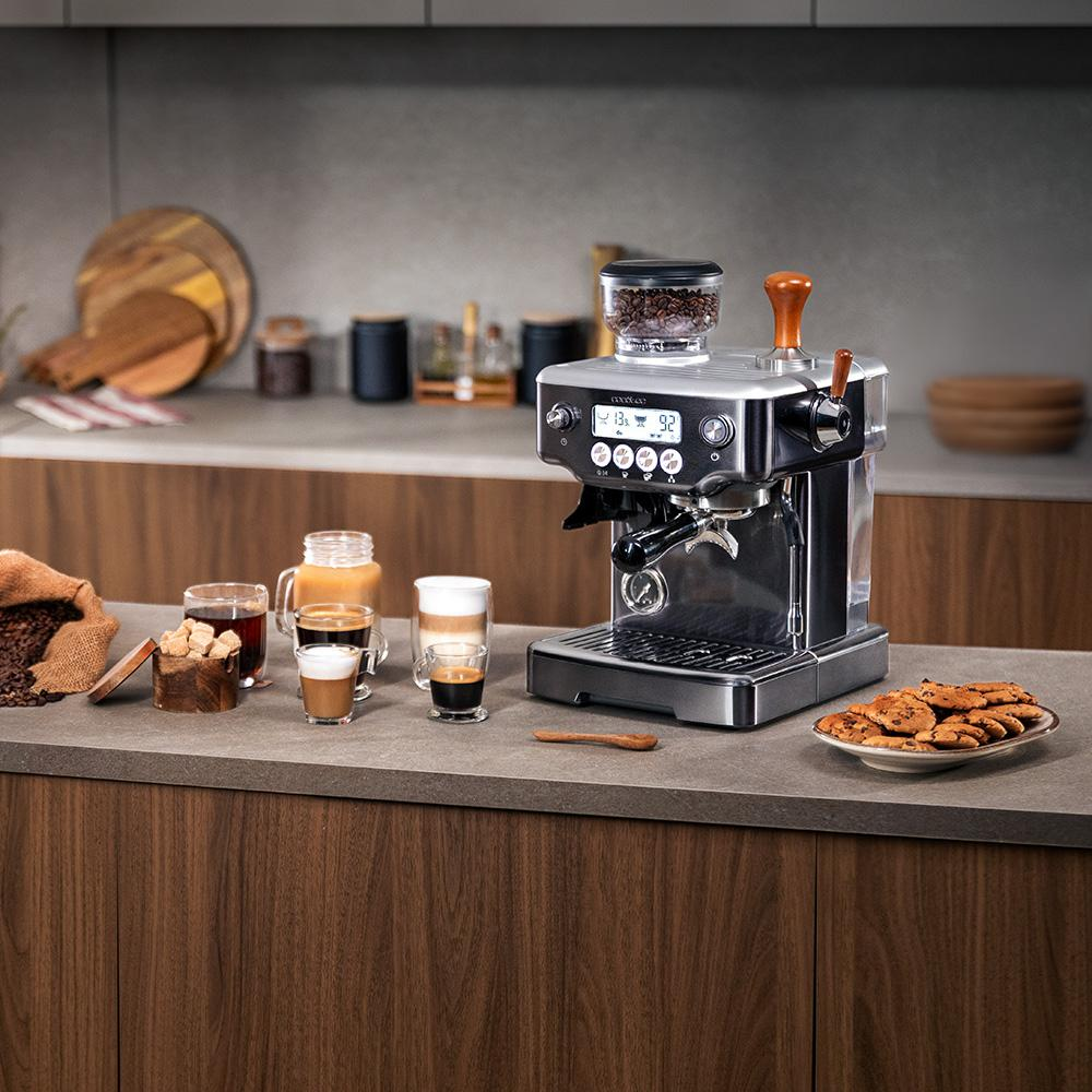 Máquina de espresso con granos de café, tazas de café y galletas en un mostrador.
