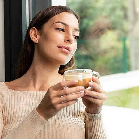 Una mujer bebe de una taza de café con vapor.