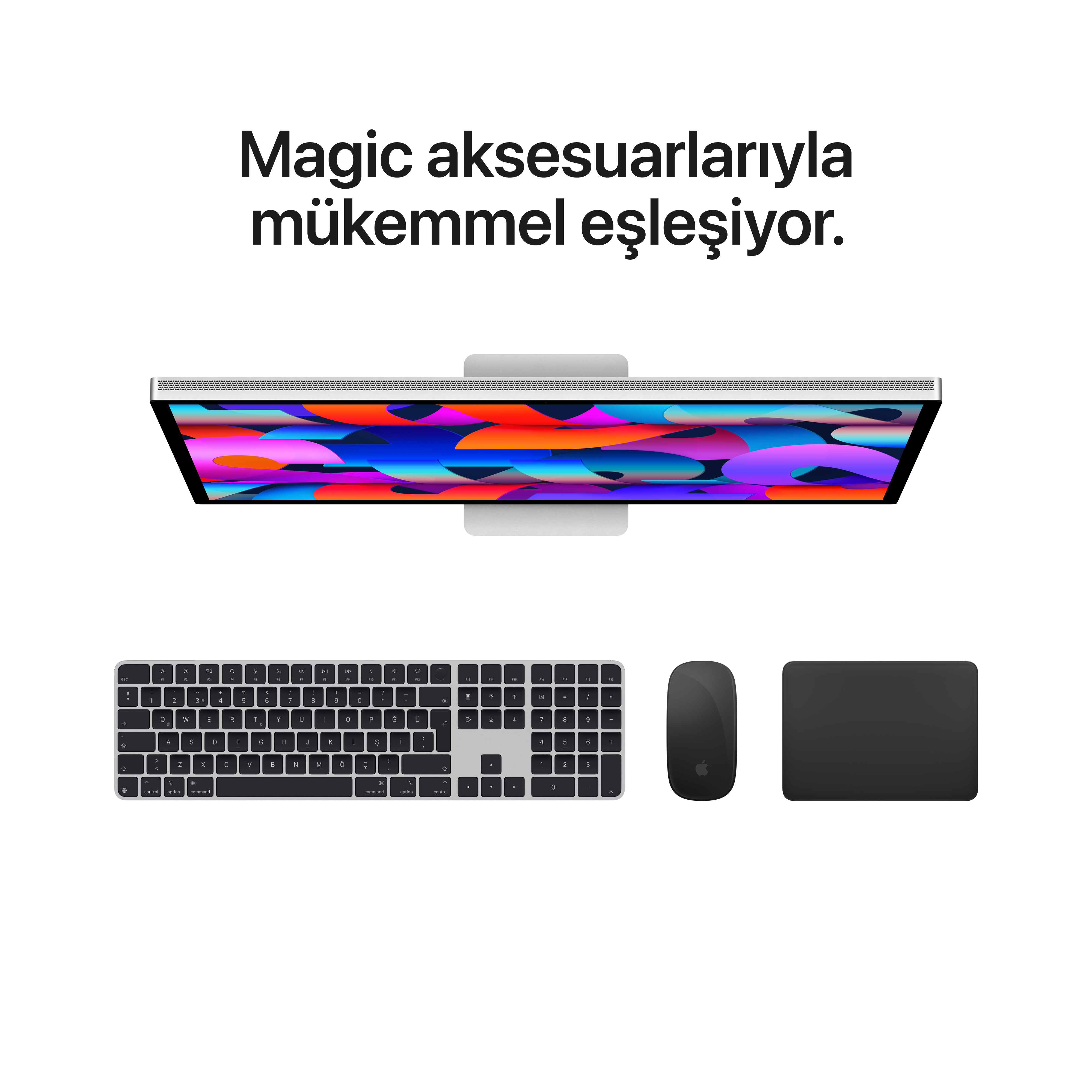 Gümüş iMac, siyah klavye, fare ve trackpad beyaz zeminde.