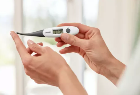 Osoba trzyma cyfrowy termometr wskazujący 37.0C.