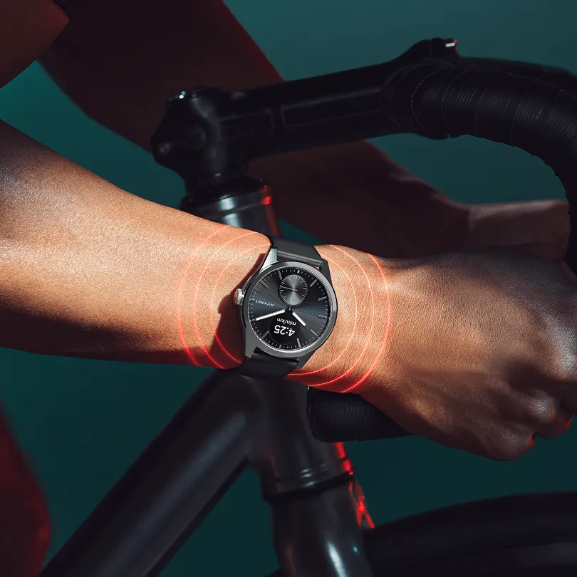 Une personne à vélo porte une montre avec des anneaux rouges indiquant l'activité.