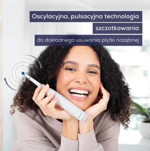 Kobieta z kręconymi włosami trzyma elektryczną szczoteczkę do zębów.