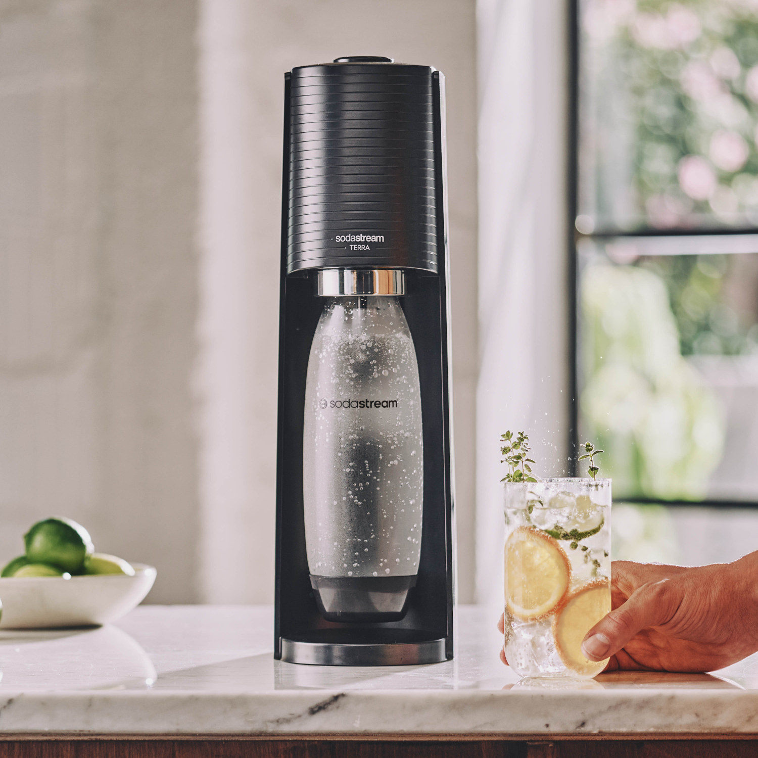 Una máquina SodaStream Terra negra con una botella y un vaso de bebida.