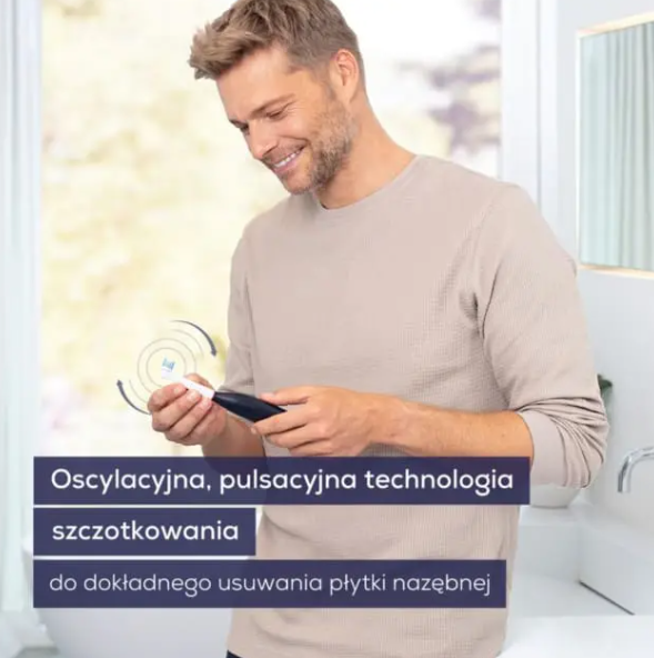 Uśmiechnięty mężczyzna trzymający elektryczną szczoteczkę do zębów, pokazującą technologię oscylacyjno-pulsacyjną.