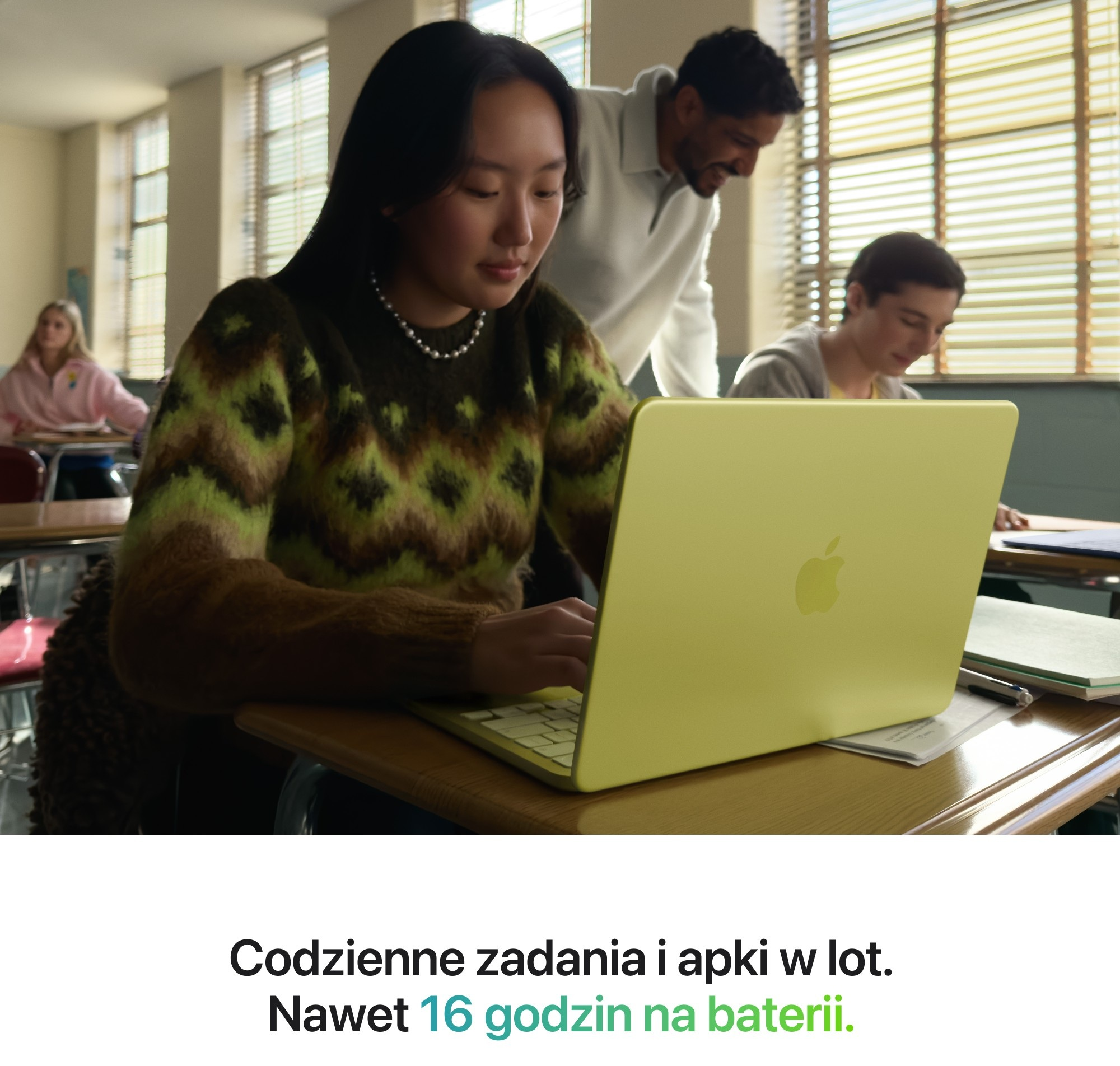 Uczniowie w klasie używający jasnozielonego laptopa.