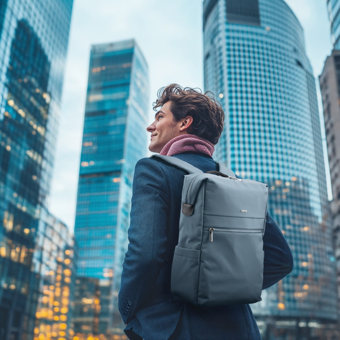 Mann mit Rucksack vor Wolkenkratzern.