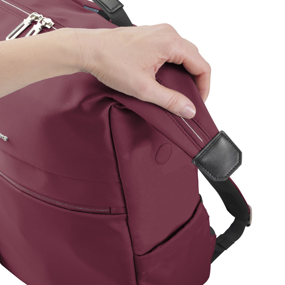 Eine Hand fasst einen dunkelroten Rucksack an einem Reißverschlussgriff.