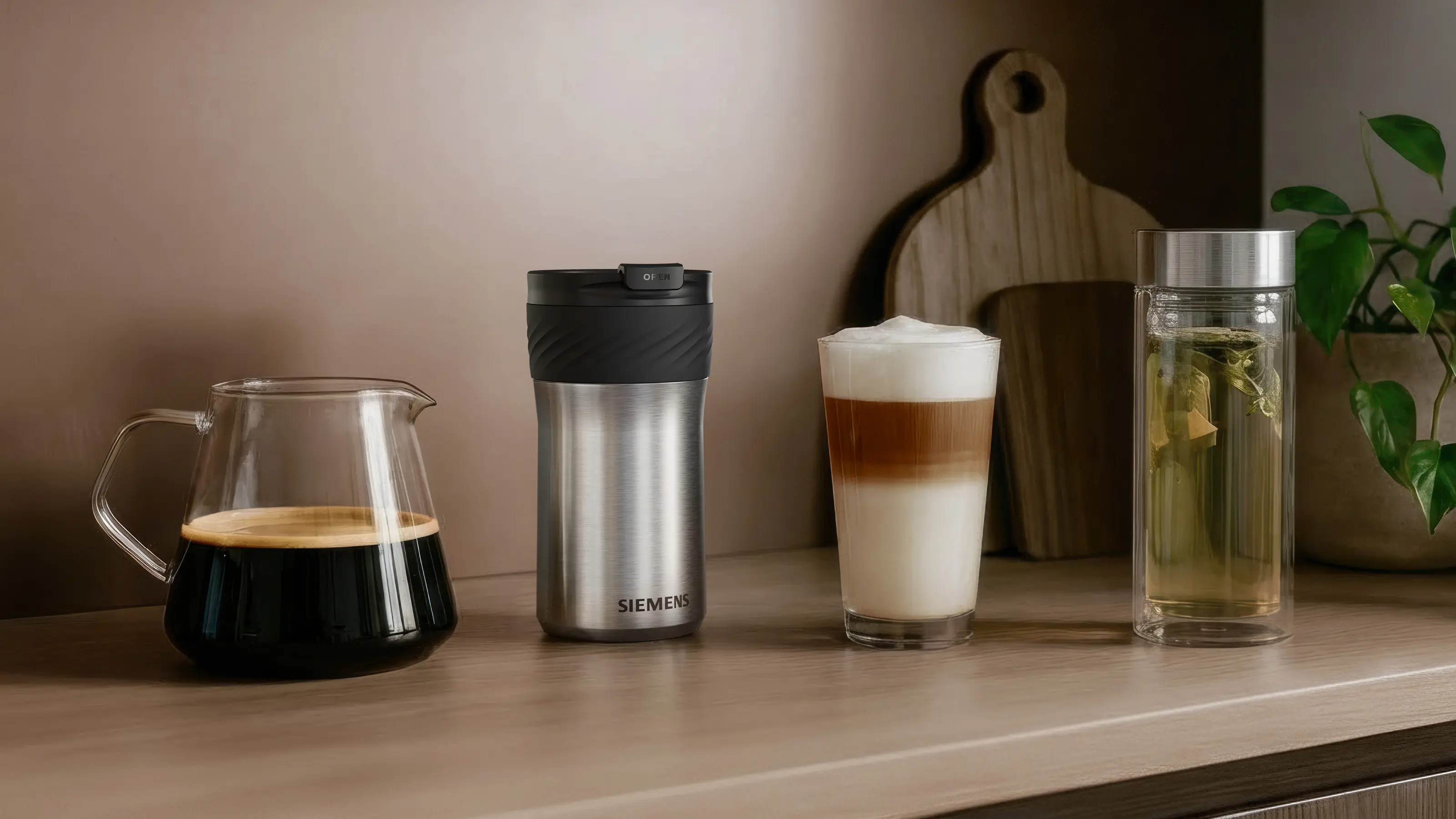 Karafka na kawę, kubek termiczny, latte macchiato i szklanka herbaty na drewnianym blacie.