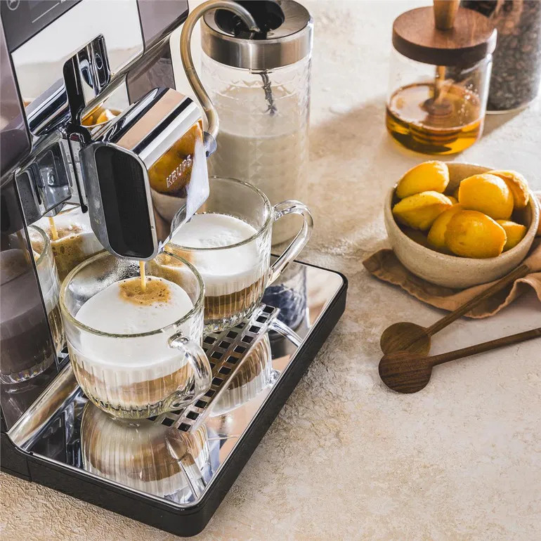 Ekspres do kawy parzy dwie cappuccino z pianką mleczną do szklanek.