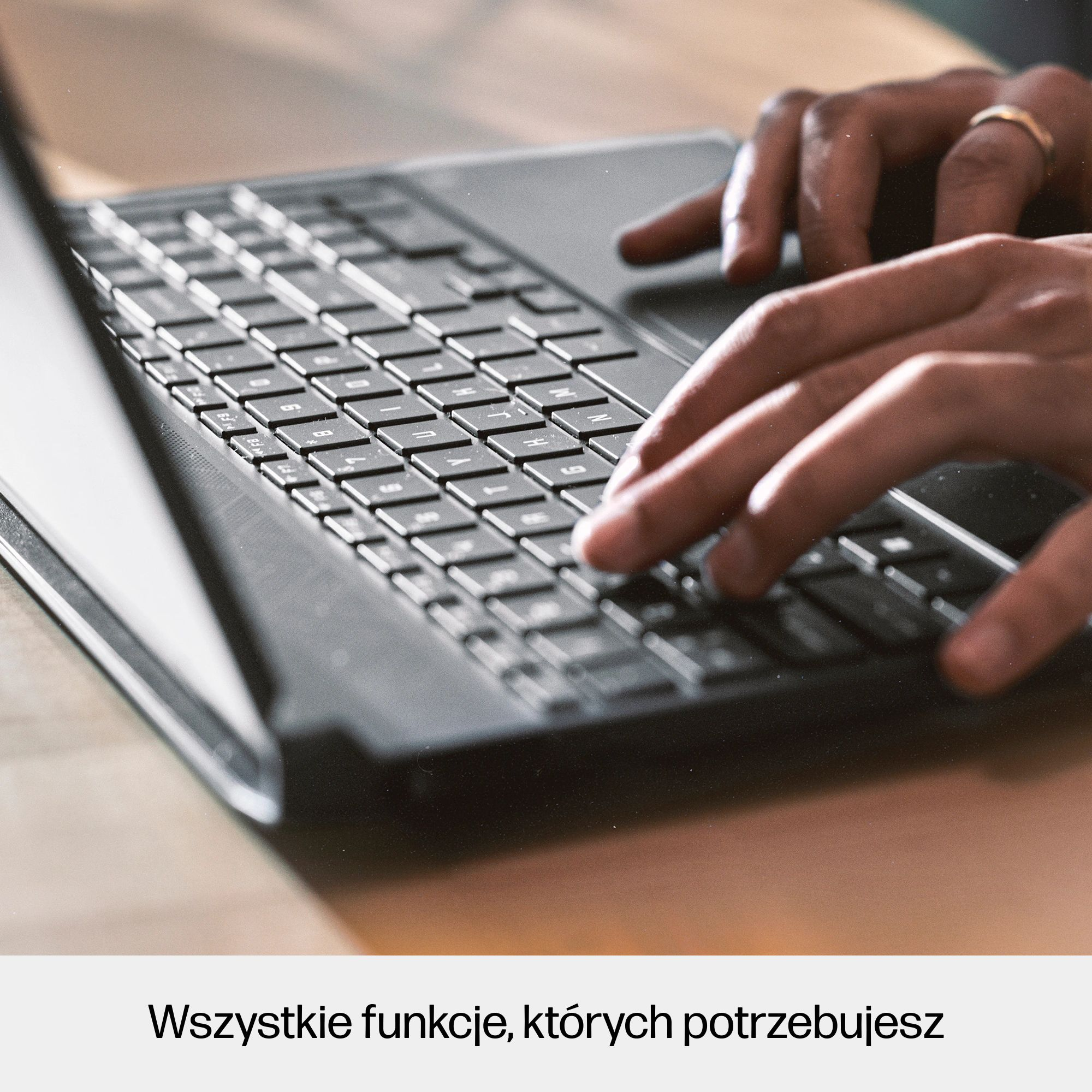 Dłonie piszące na czarnej klawiaturze, widoczny pierścionek.