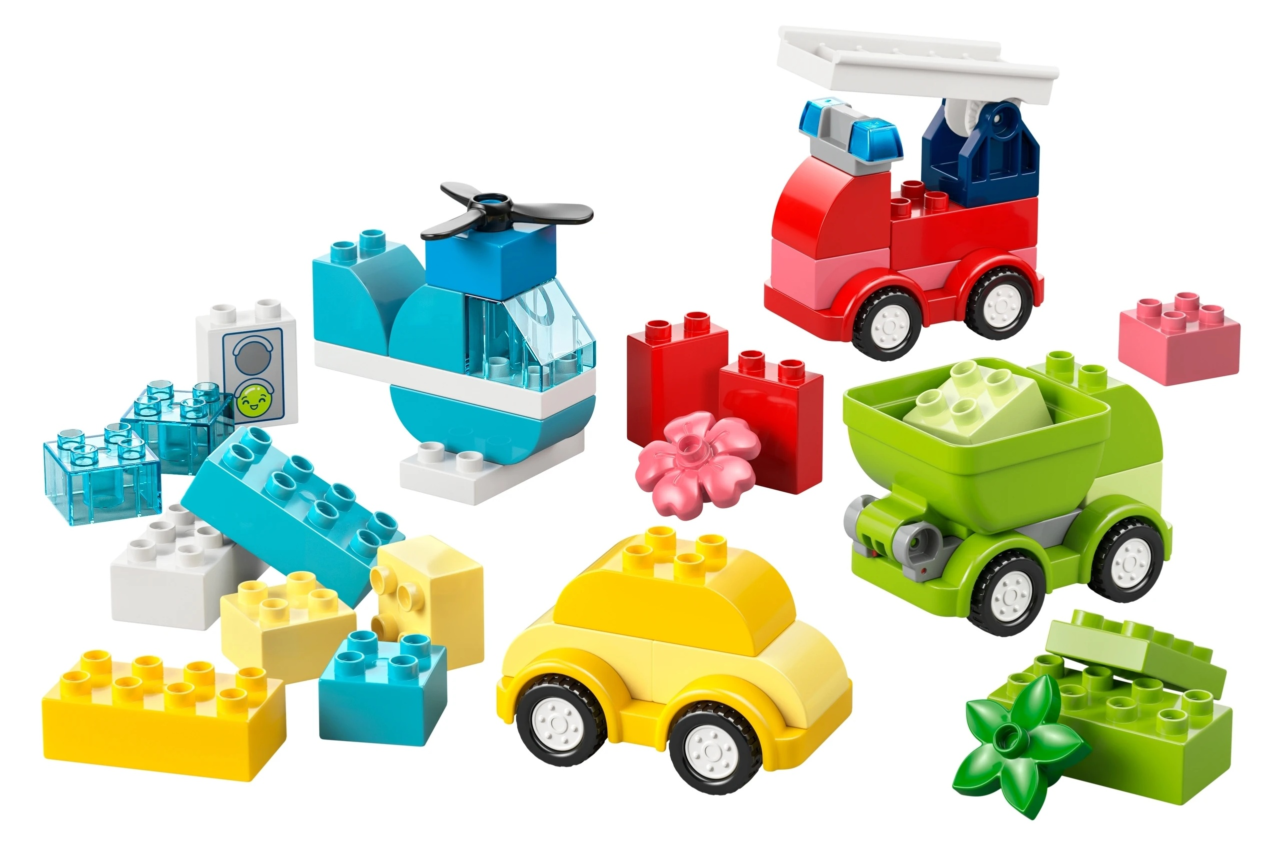Kolorowe klocki LEGO, helikopter, wóz strażacki, wywrotka, samochód i kwiatek.