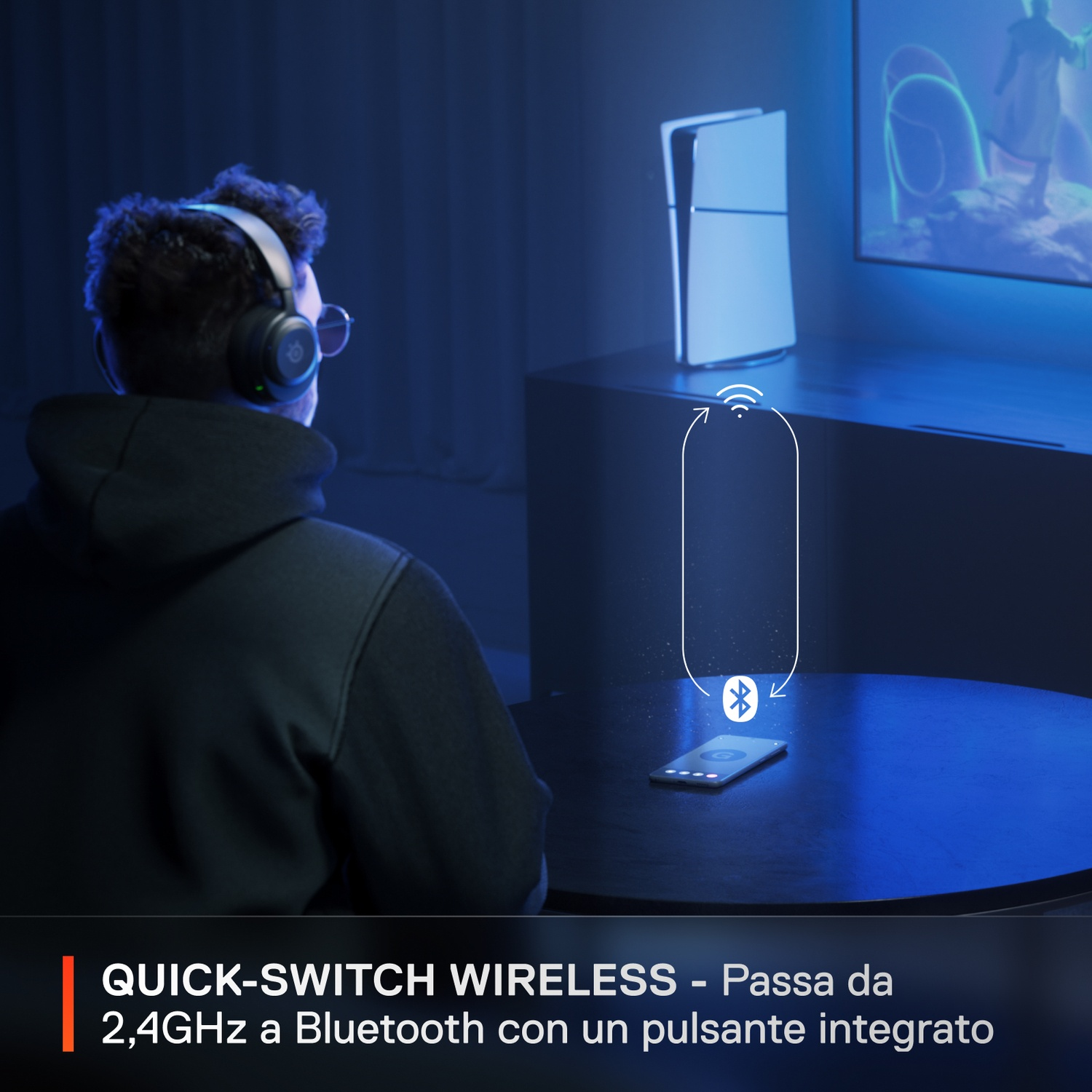 Uomo con cuffie gioca ai videogiochi. Console e telefono sul tavolo.