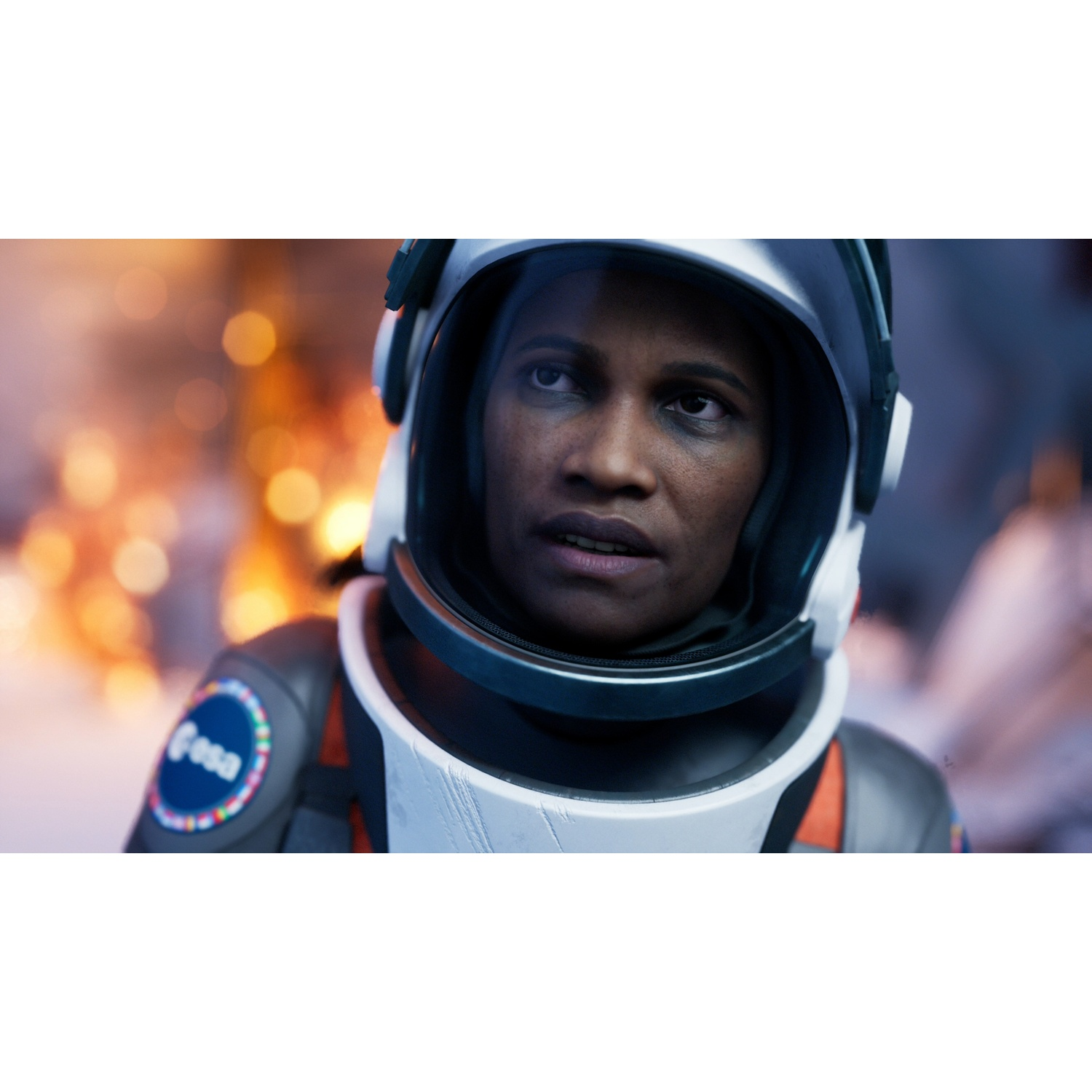 Astronaut in helm kijkt naar links. ESA-logo op schouder. Wazige achtergrond.