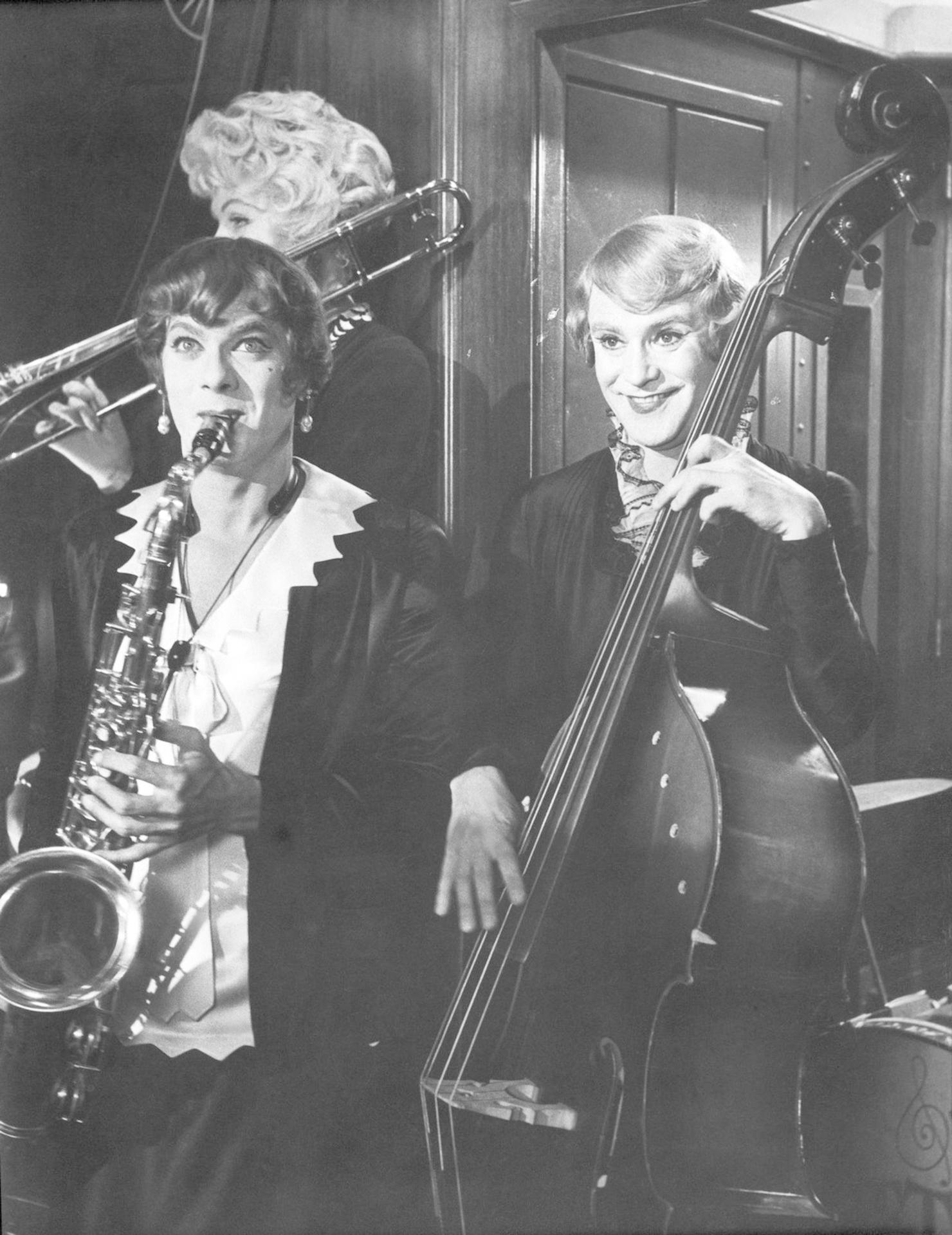 Drei Frauen spielen Instrumente in einer Band. Eine spielt Saxophon, eine Kontrabass, eine Posaune.