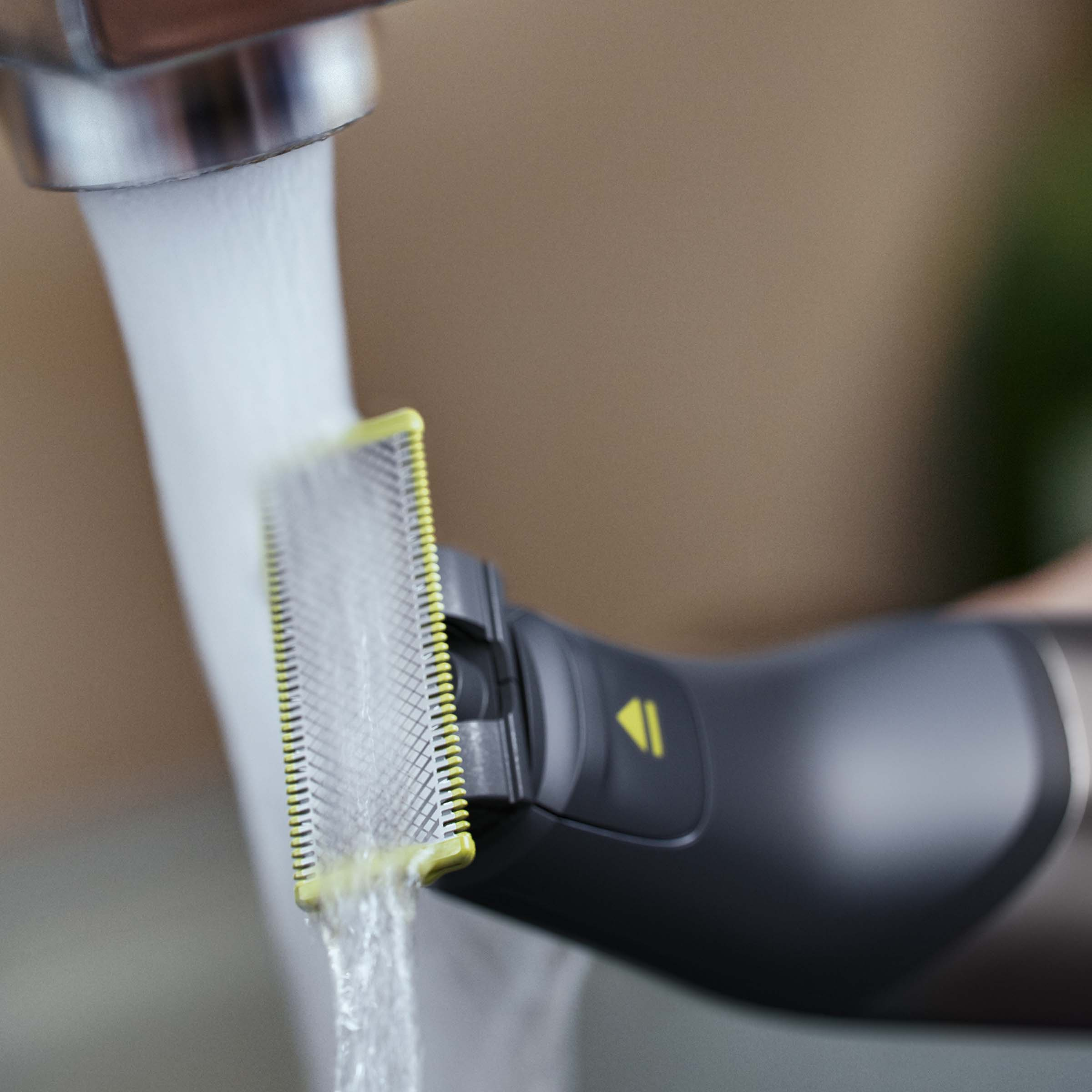 Ciemna golarka z żółtą krawędzią pod bieżącą wodą.