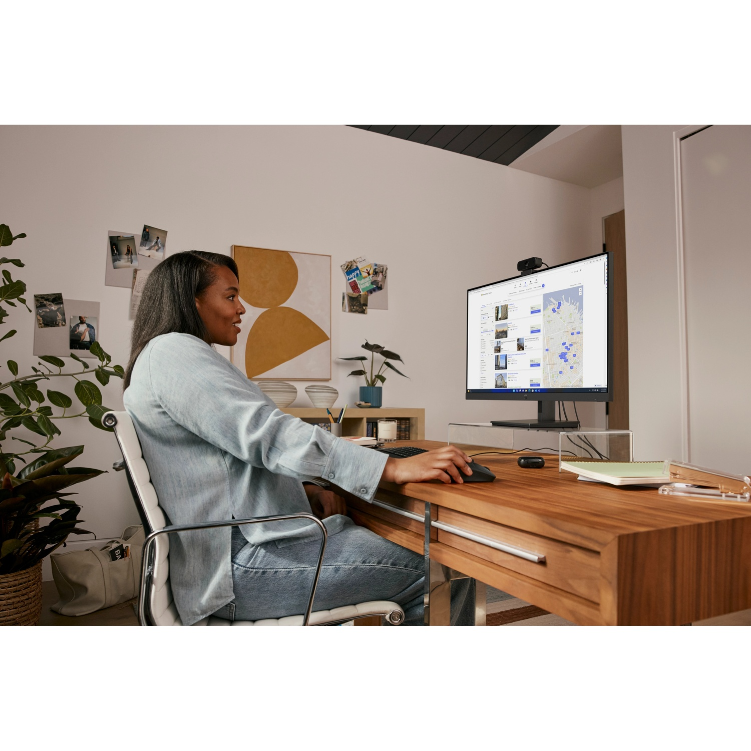 A woman sits at a desk using a computer.