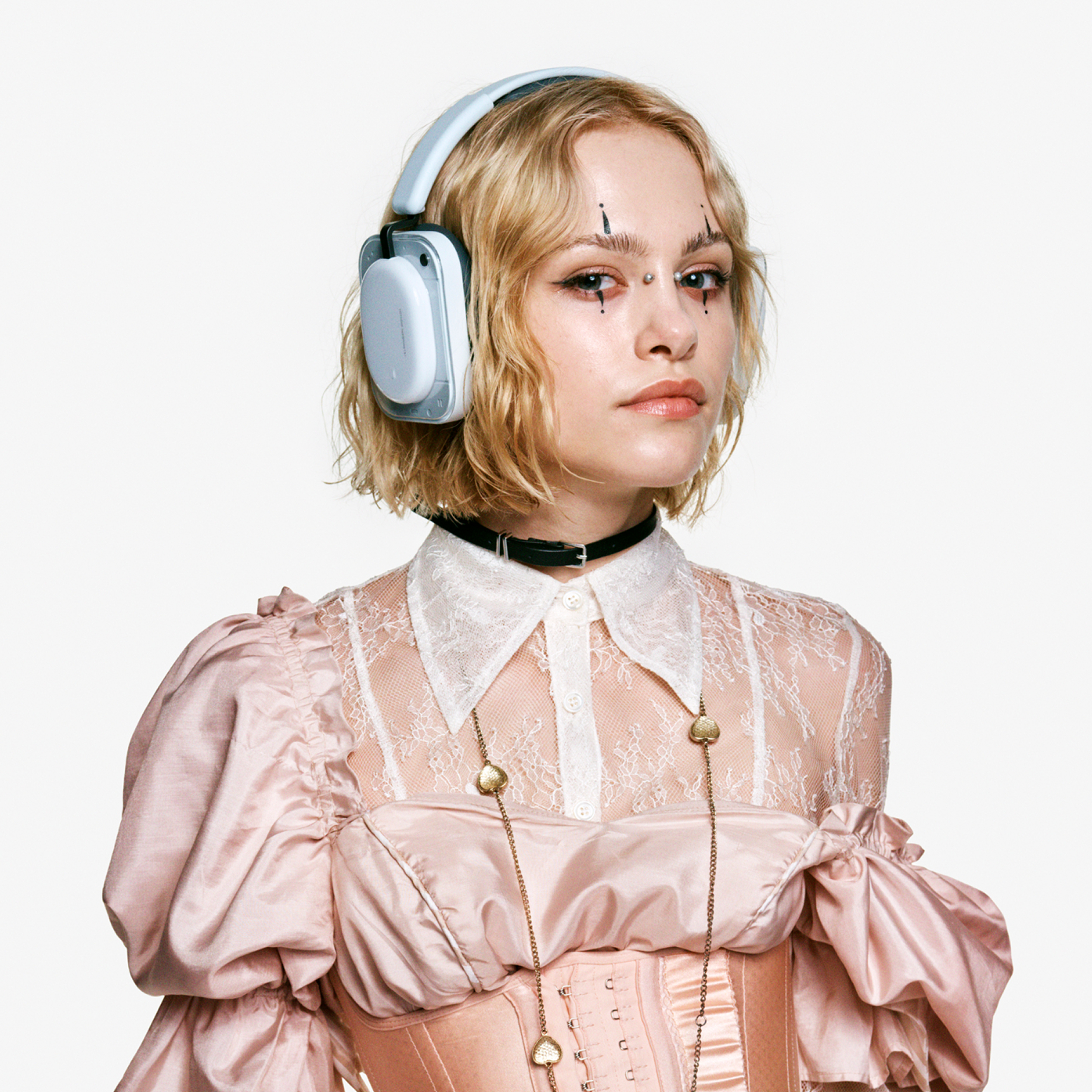 Eine junge Frau mit blonden Haaren trägt Kopfhörer und eine rosa Korsett-Kleidung.