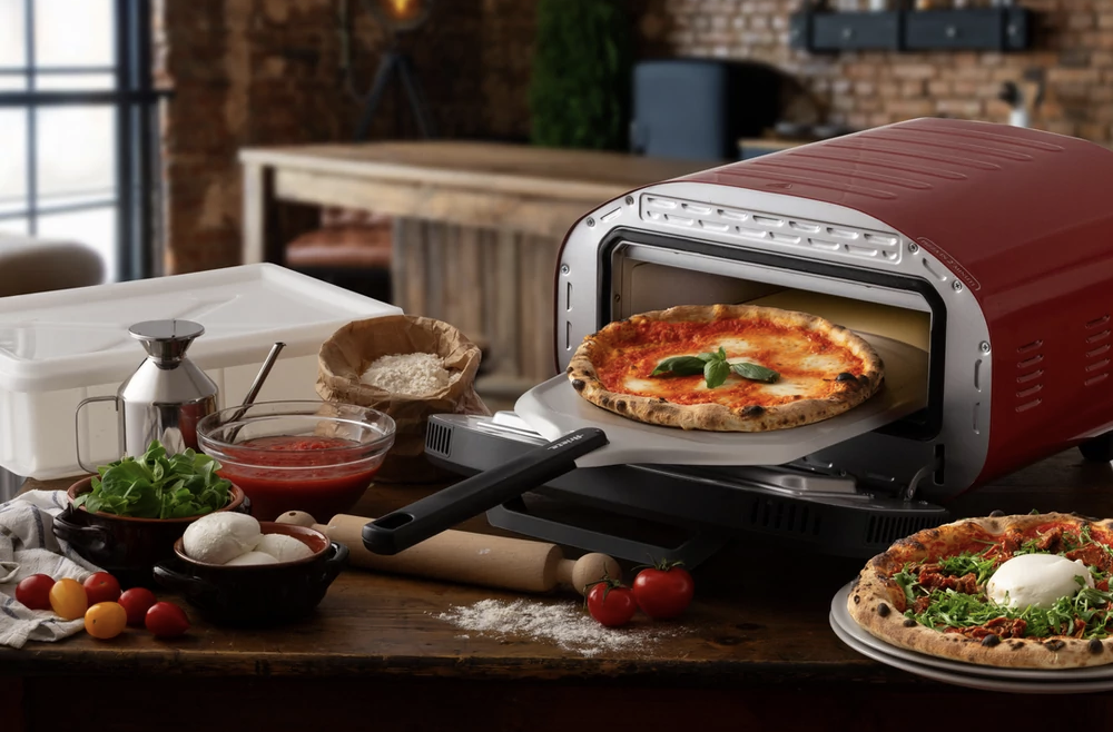 Piros pizza sütő, benne egy margherita pizzával, mellette egy másik.