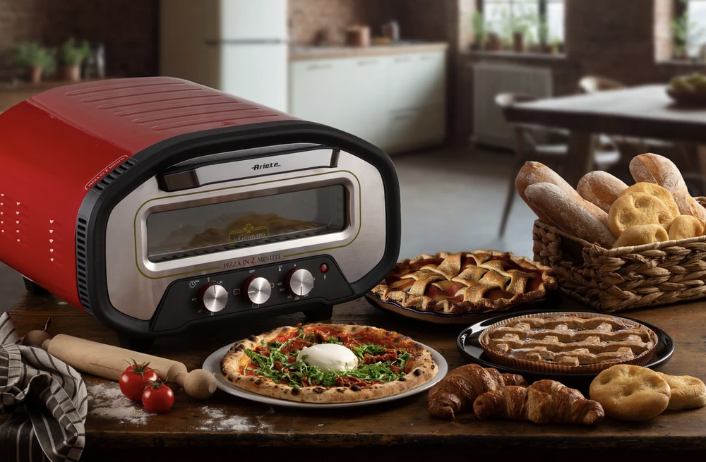 Piros sütő pizzával, tortákkal és kenyérrel faasztalon.