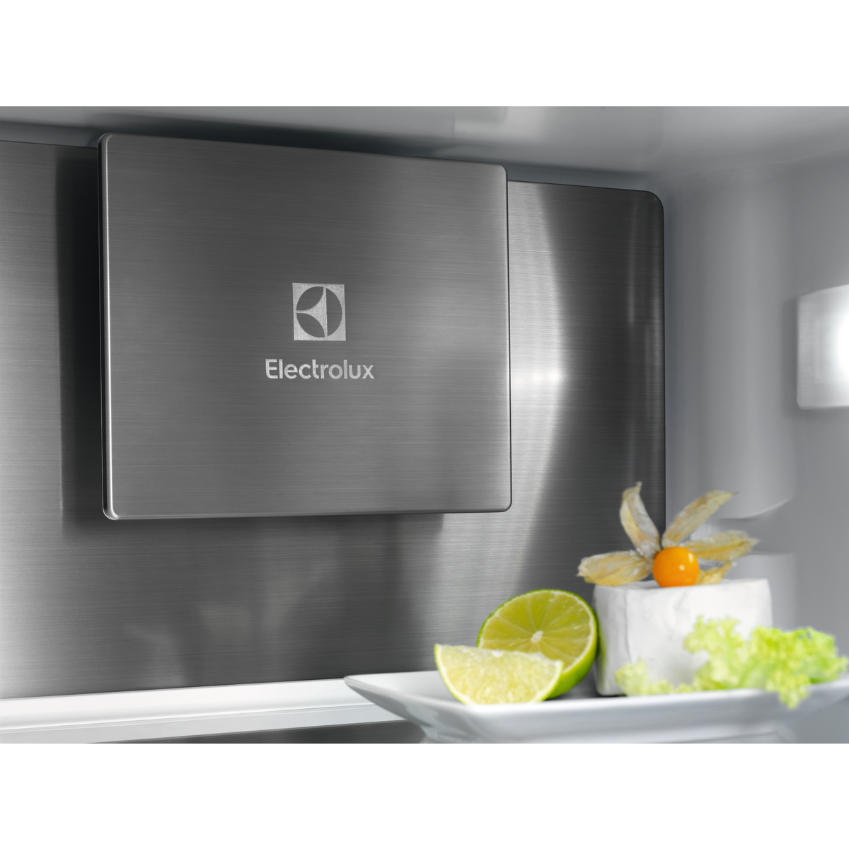 Szálcsiszolt fém panel Electrolux logóval, sajttal, lime-mal és salátával tányéron.