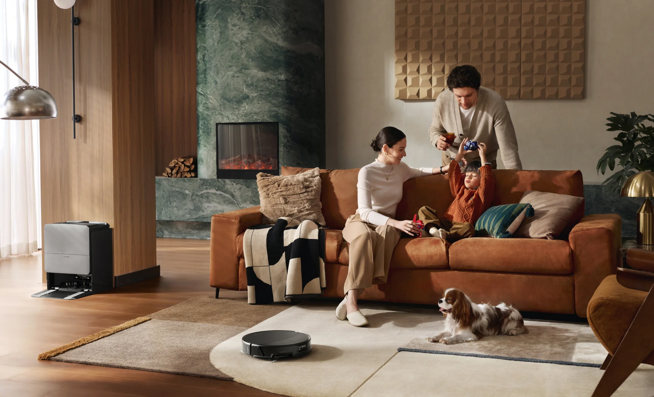 Famille se détendant dans le salon pendant que l'aspirateur robot nettoie. Chien au sol.