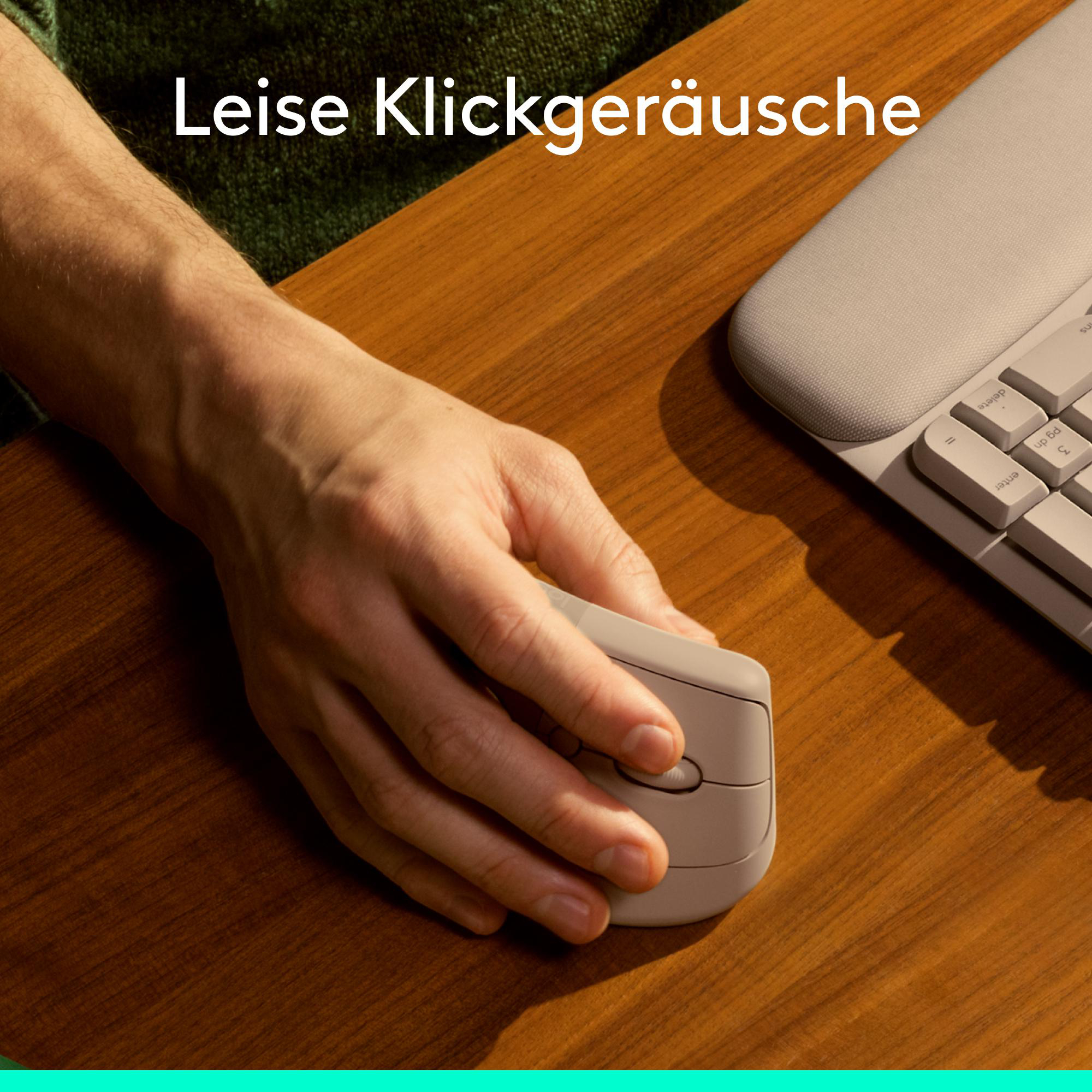 Hand bedient eine leise Computermaus auf einem Holztisch neben einer Tastatur.