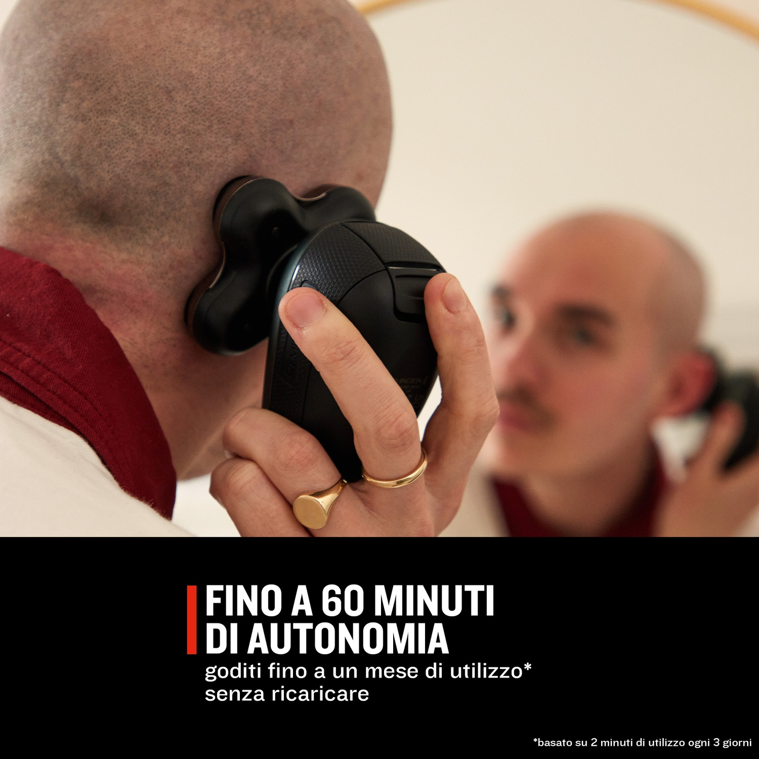 Un uomo si rade la testa con un rasoio elettrico nero, riflesso in uno specchio.
