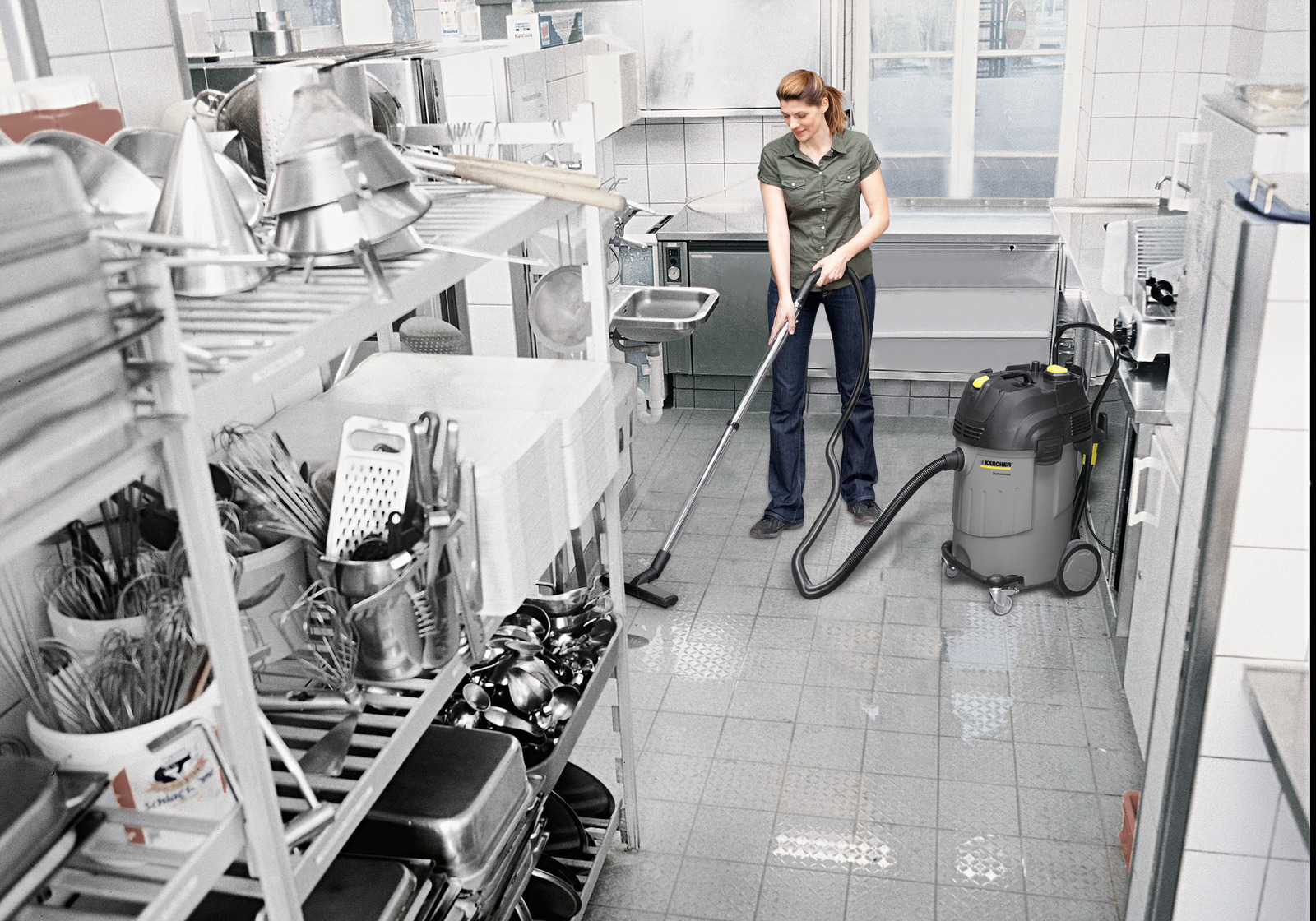 Egy nő porszívózik egy konyhában egy Karcher porszívóval.
