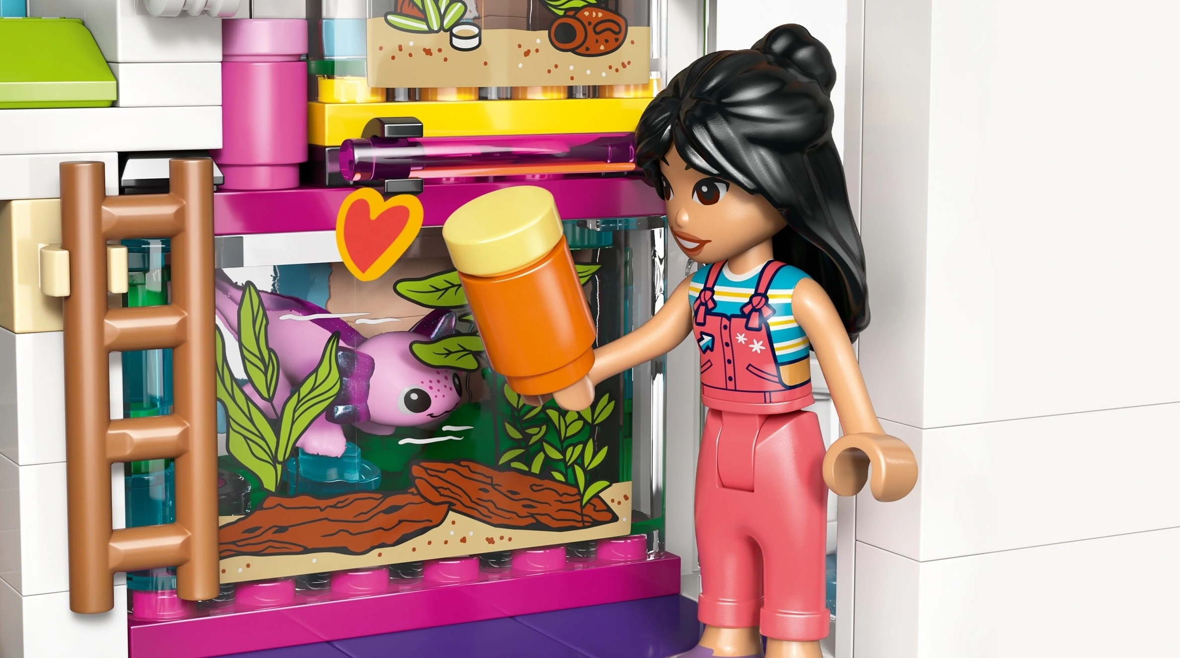 Dziewczynka Lego w ogrodniczkach karmi różowego aksolotla w akwarium.