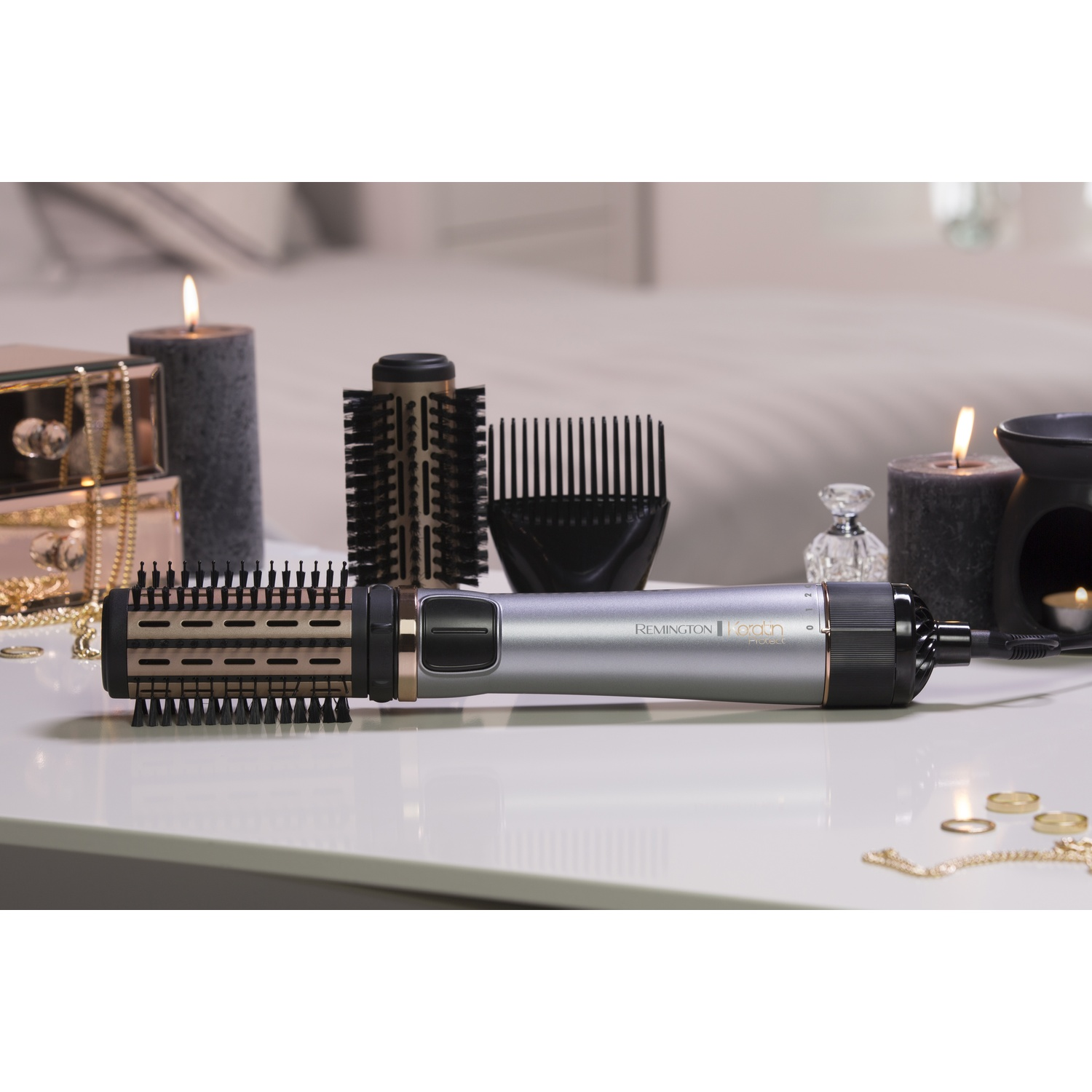 Un styler per capelli Remington con accessori, candele e gioielli su un tavolo.