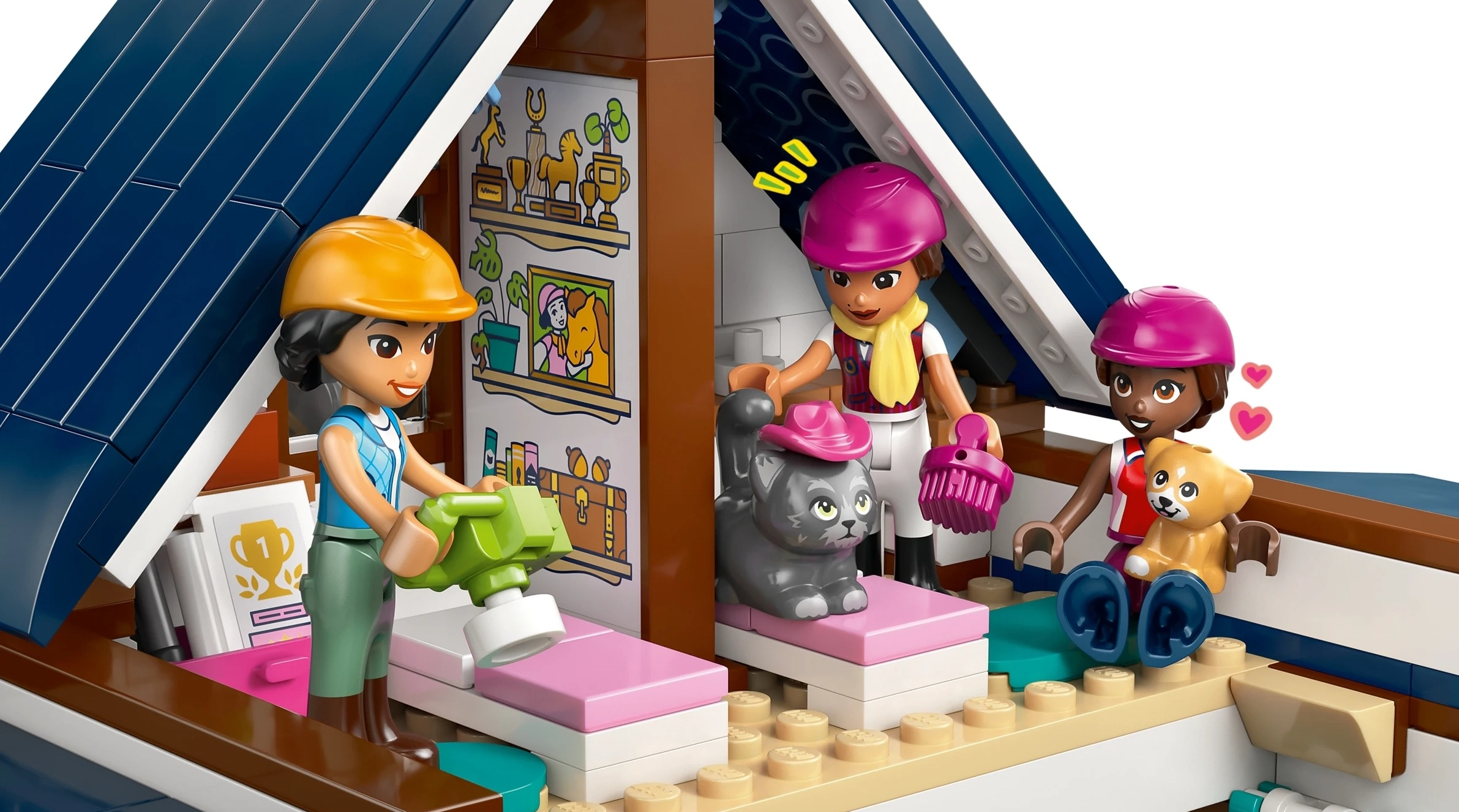 Trzy dziewczynki w stajni. Jedna szczotkuje kota, druga trzyma misia.