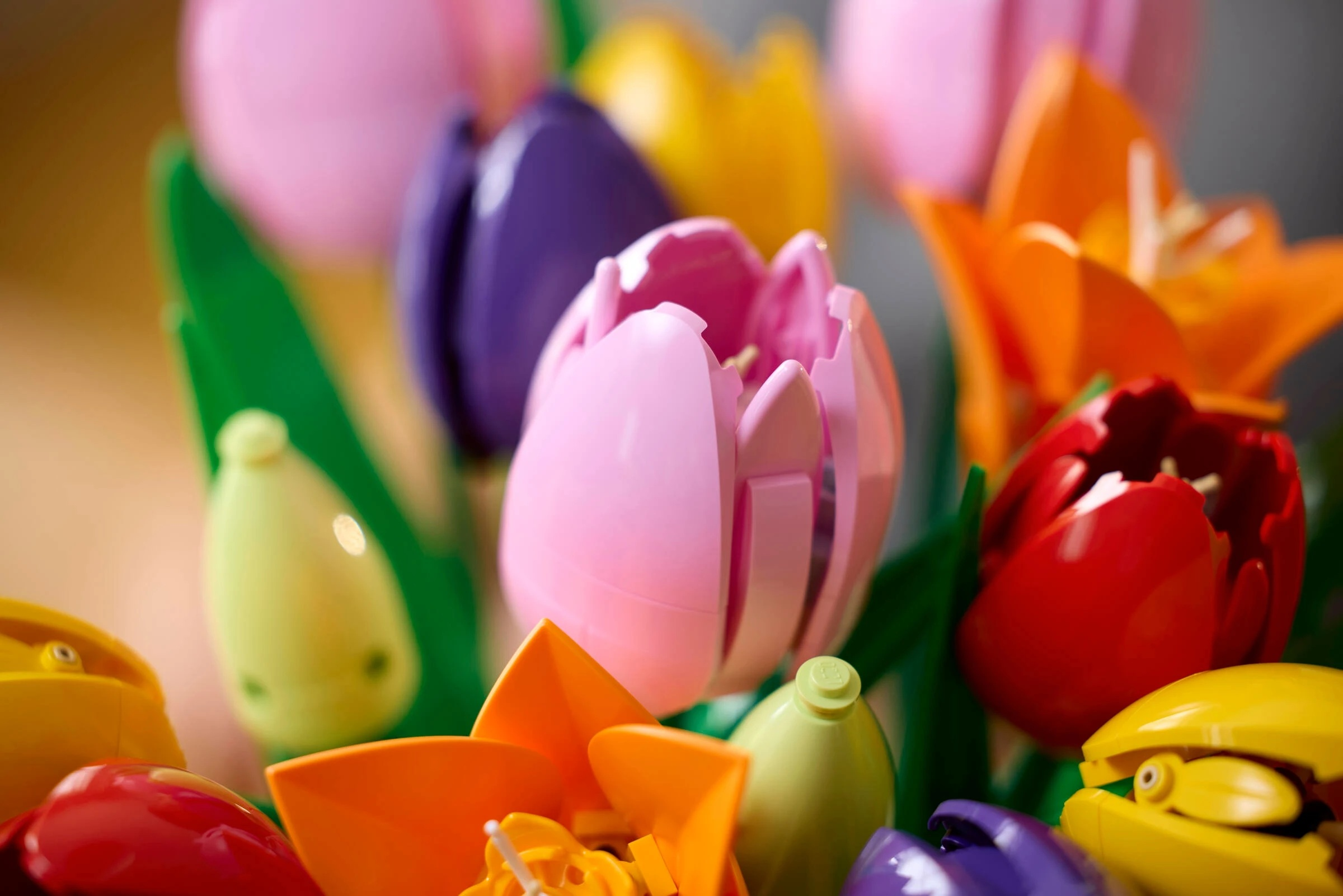 Kolorowe plastikowe tulipany z zielonymi liśćmi.