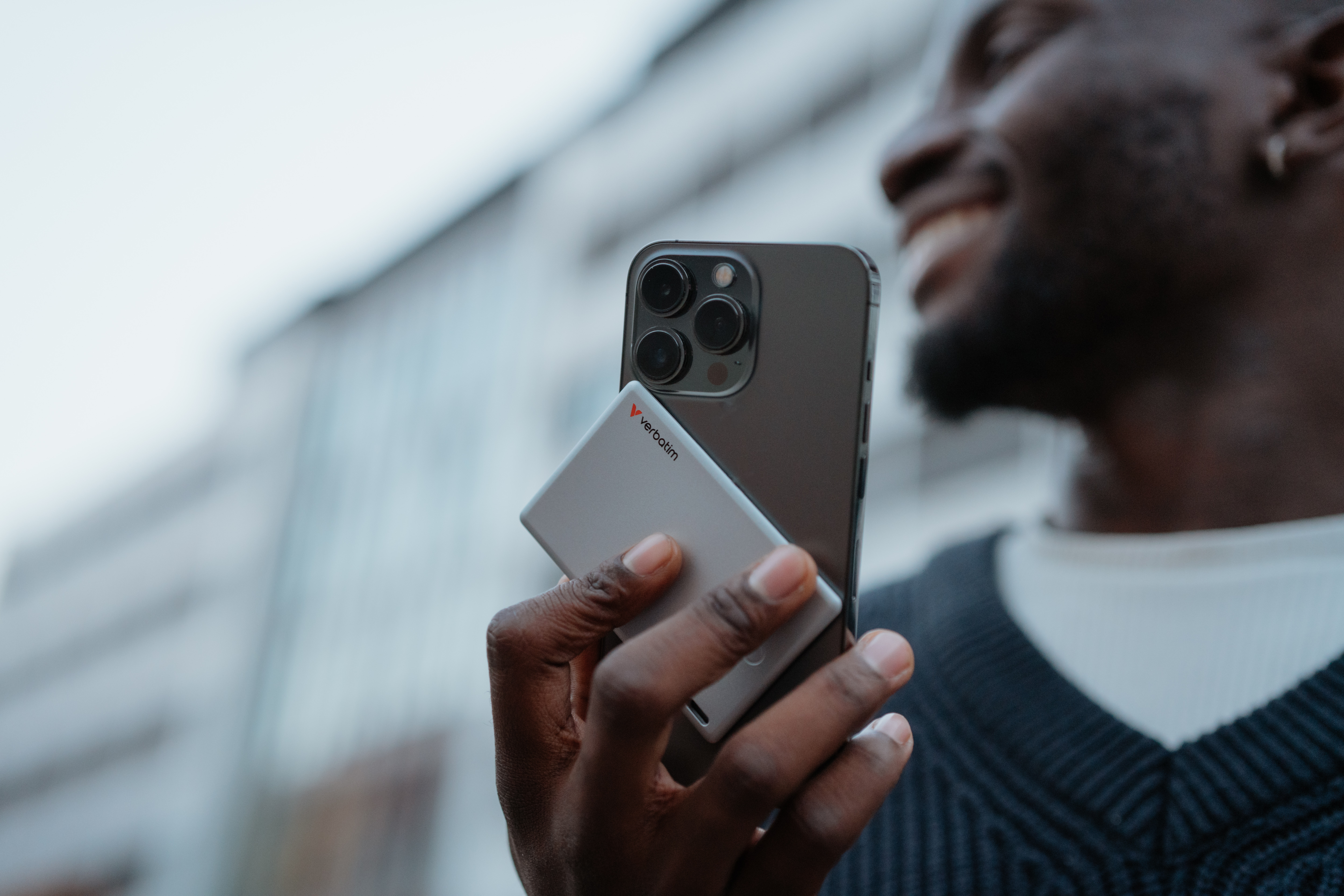 Mann hält Handy mit Speicherkarte. Hintergrund unscharf.