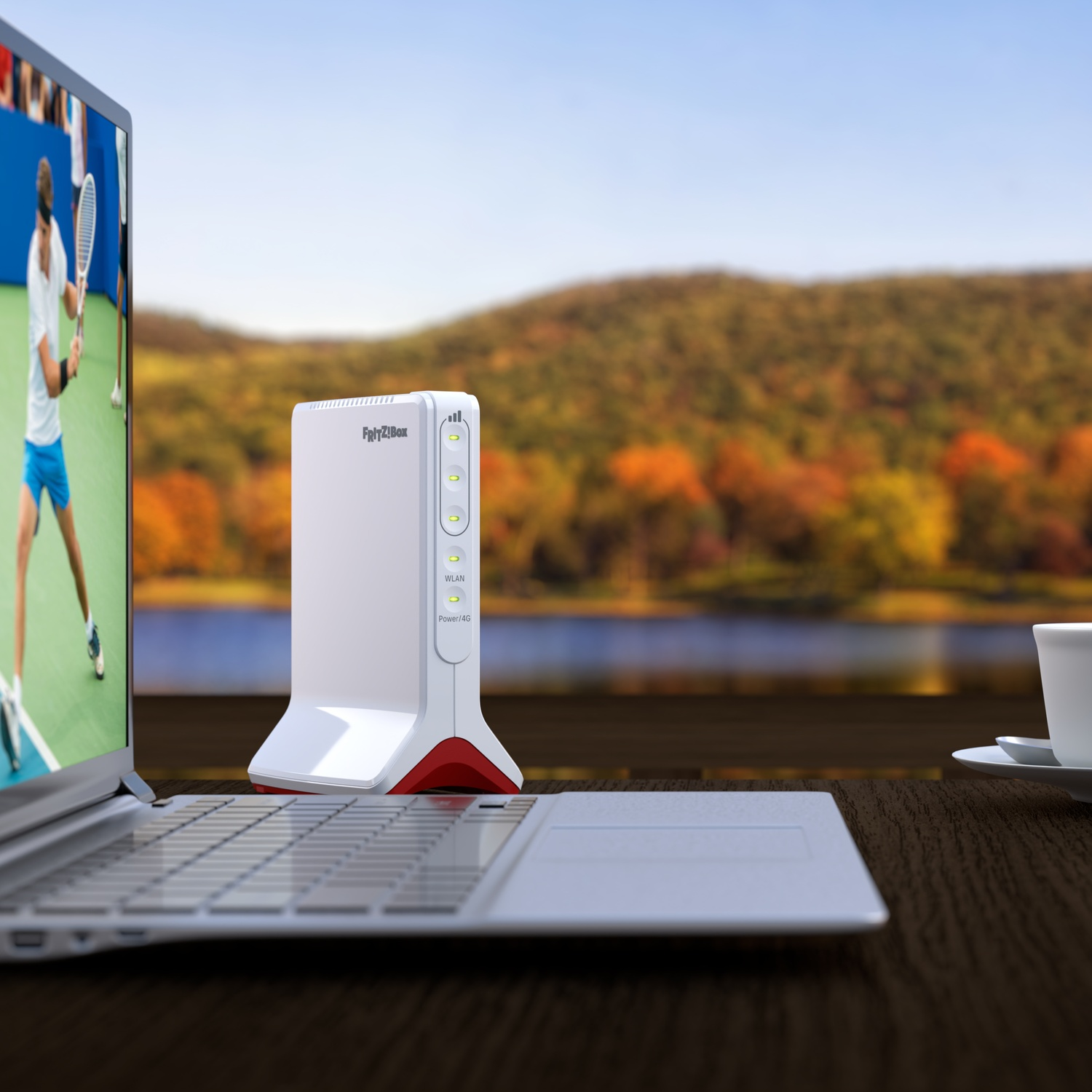 Un laptop mostra il tennis, accanto un router e una tazza di caffè, sfondo foresta autunnale.