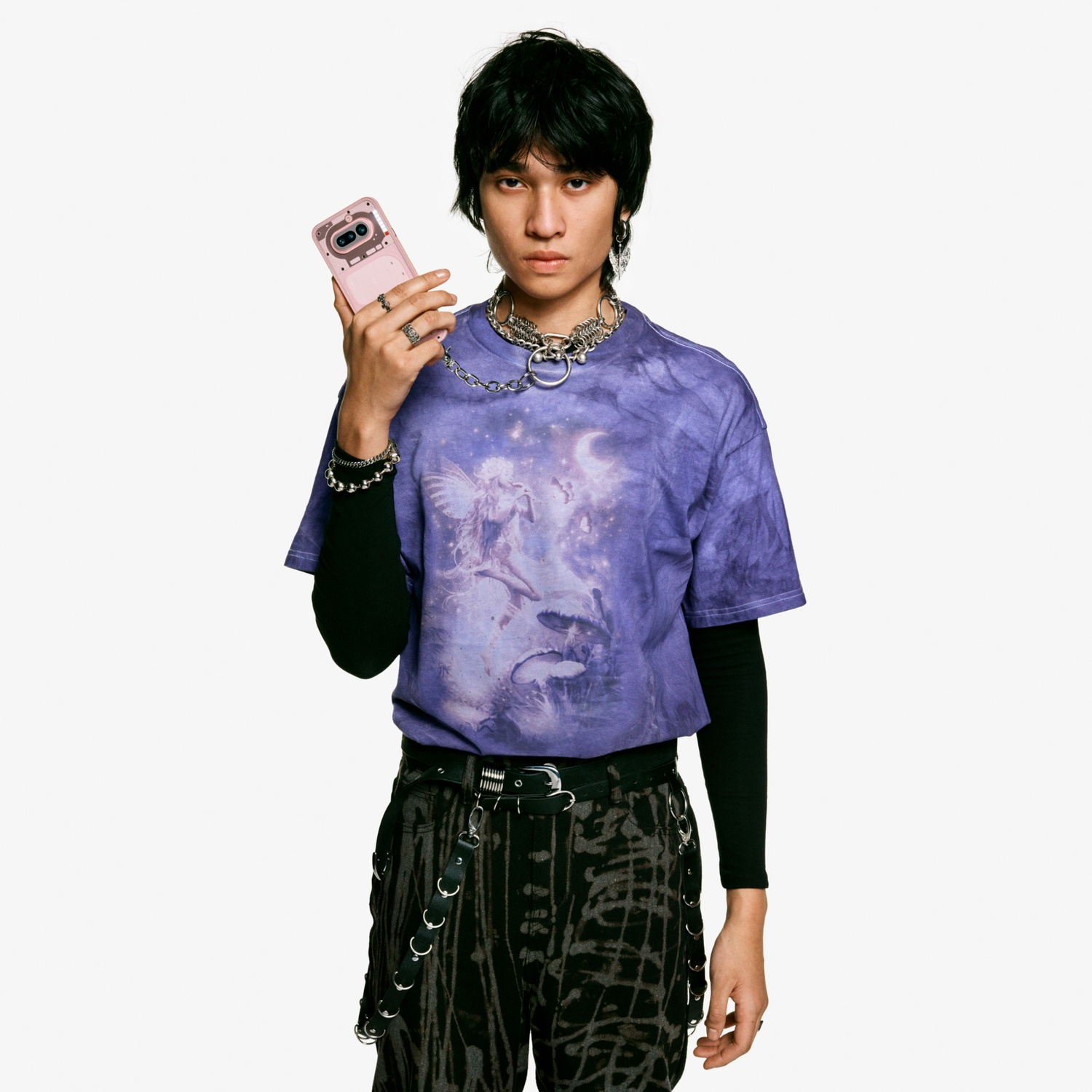 Una persona con i capelli scuri tiene una custodia rosa per telefono. Indossa una maglietta viola.