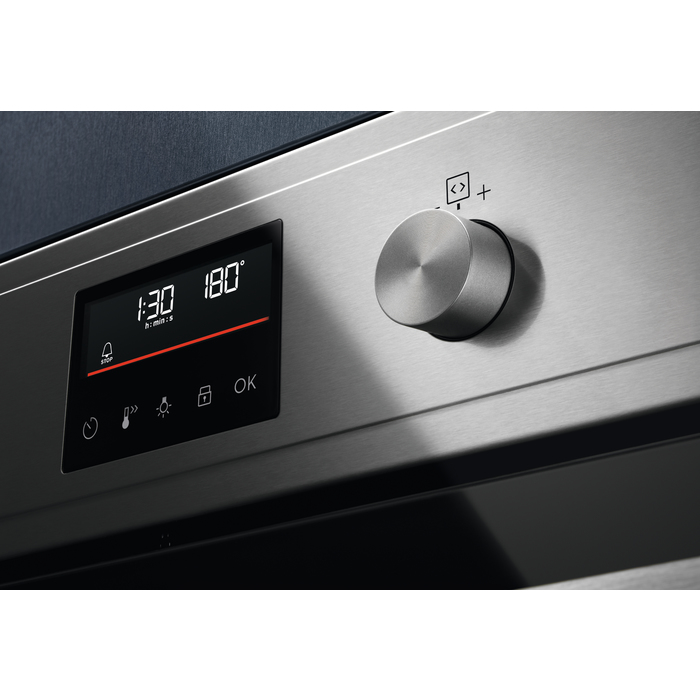 Primer plano de la pantalla de un horno con hora y temperatura, y un mando giratorio.