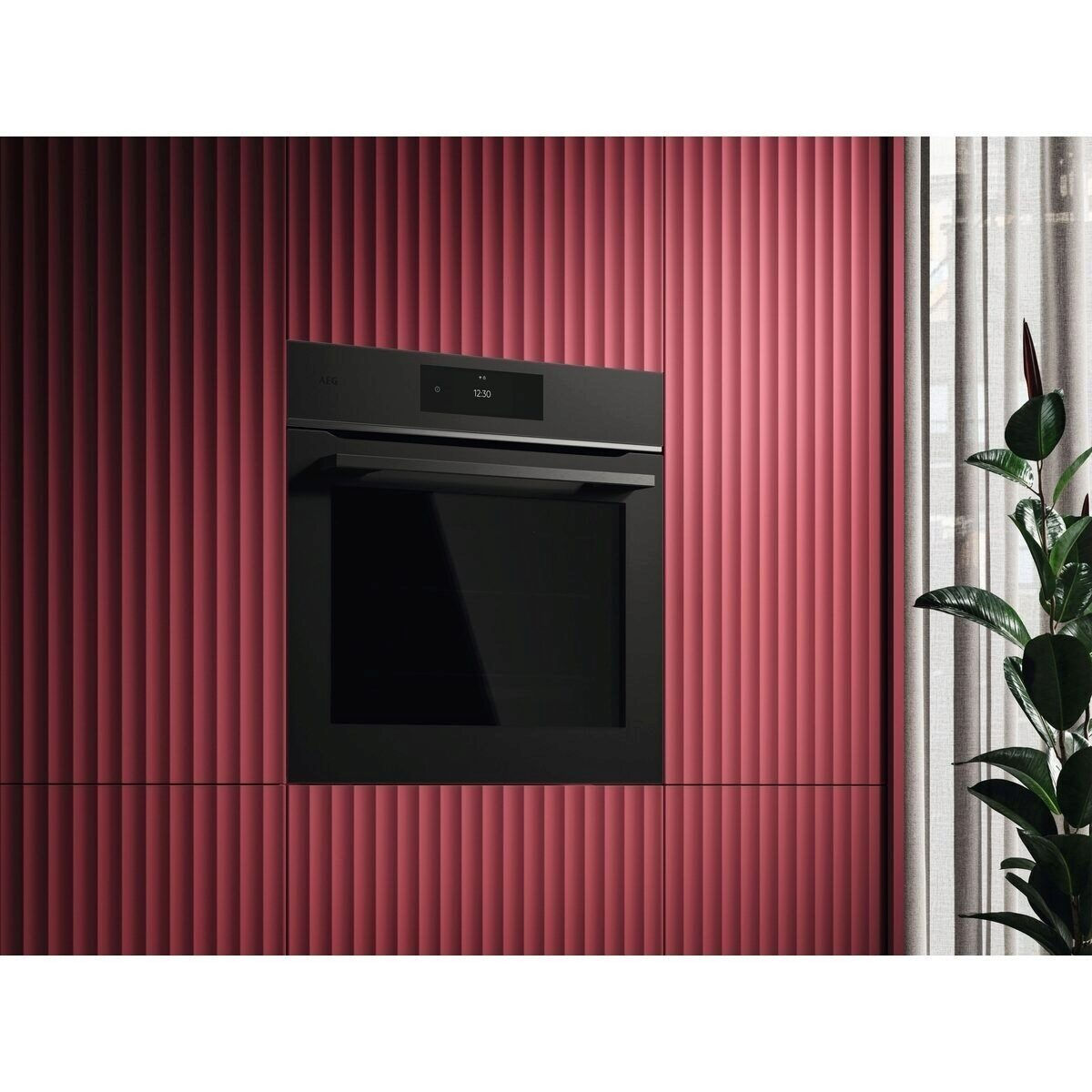 Un horno empotrado negro moderno frente a una pared roja acanalada.