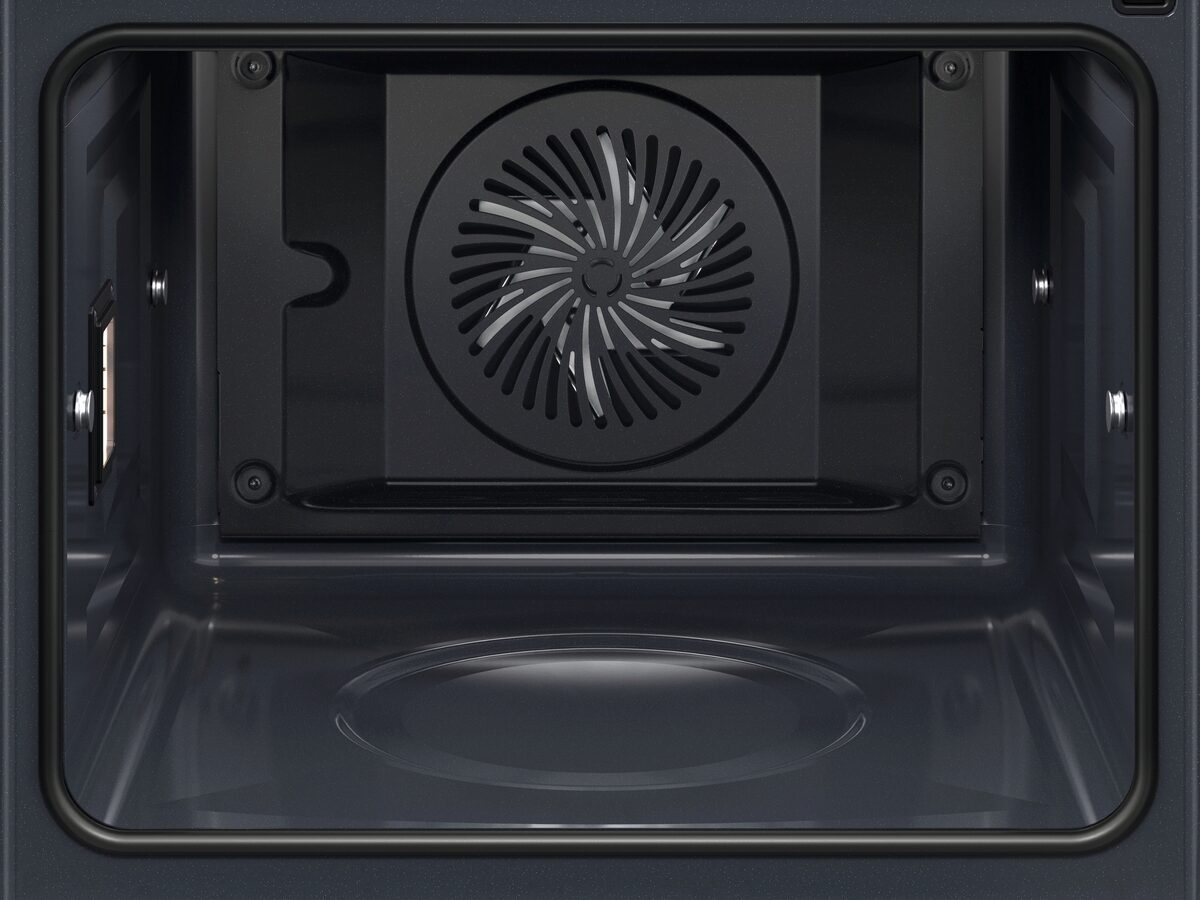 Interior de un horno oscuro con rejilla de ventilador y luz.