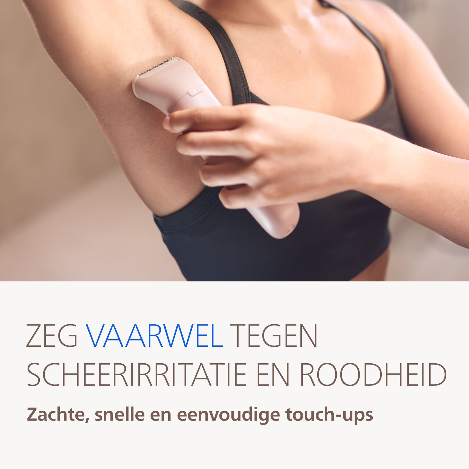 A woman shaves her armpit with a pink epilator.